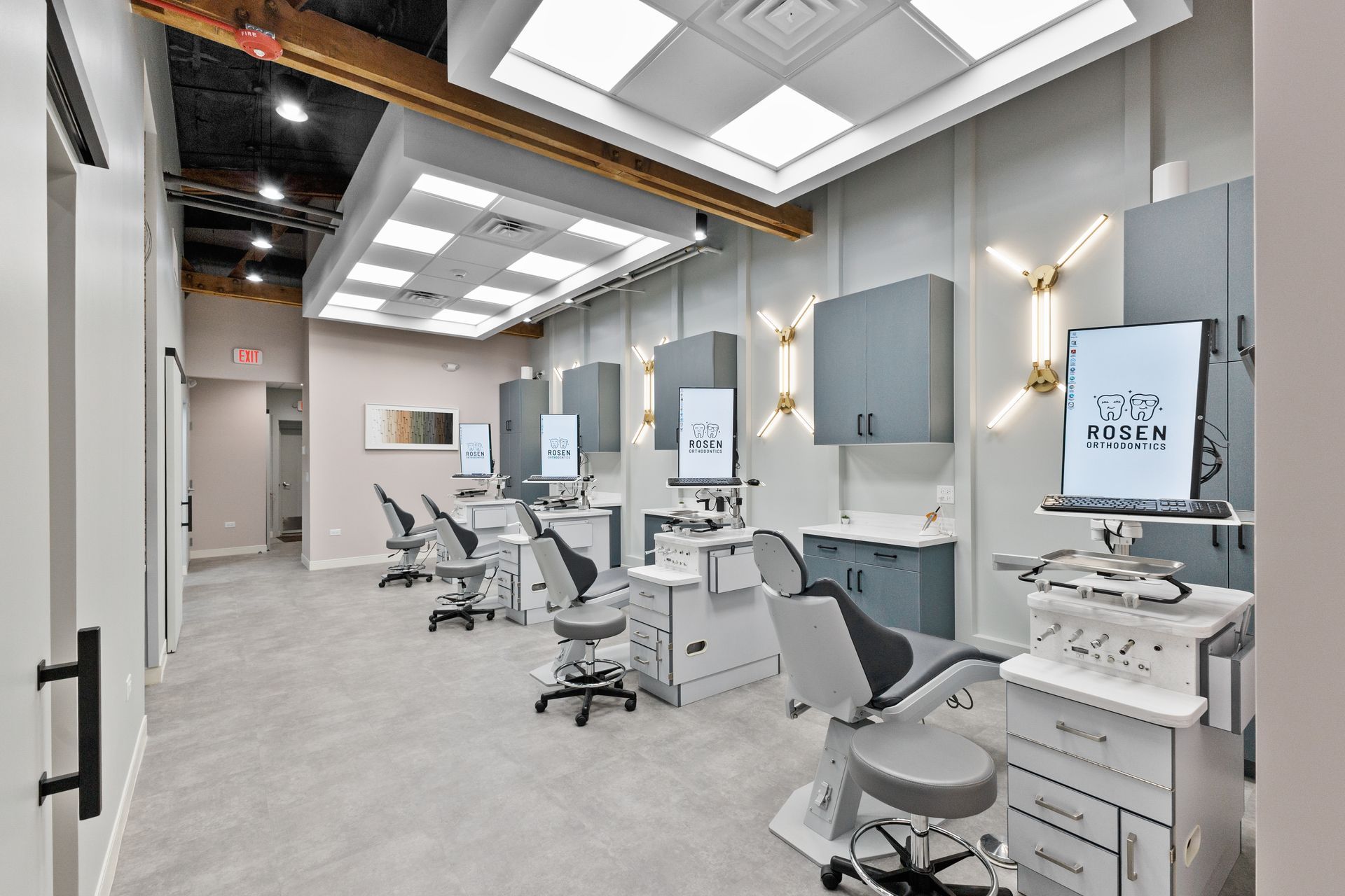 Bright dental clinic with rows of gray chairs, exam lights, and cabinets in a clean modern office