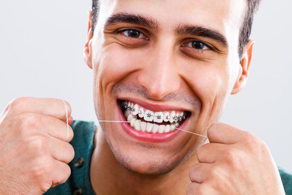 Man using dental floss — Buffalo Grove, IL — Rosen Orthodontics Man using dental floss — Buffalo Grove, IL — Rosen Orthodontics