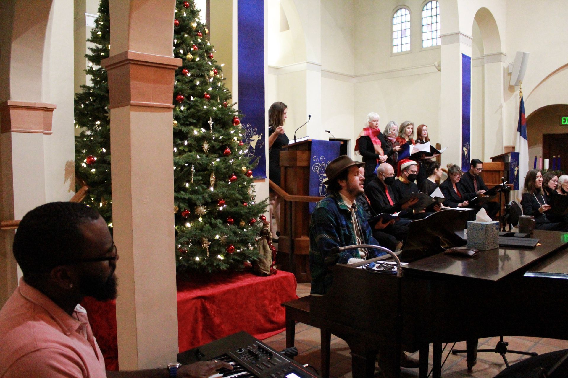 Church service with a choir, Christmas trees, and a piano player.