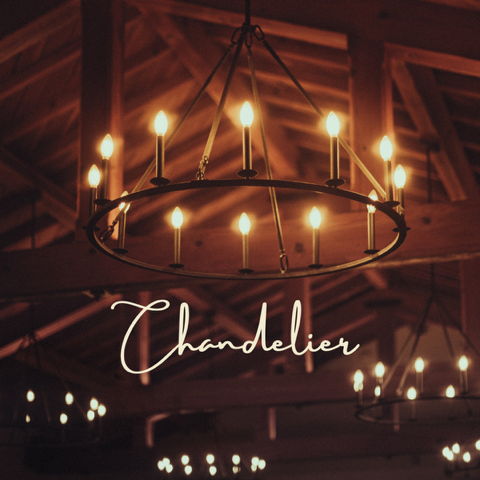 Chandelier hanging from a wooden ceiling, candles lit, warm lighting.