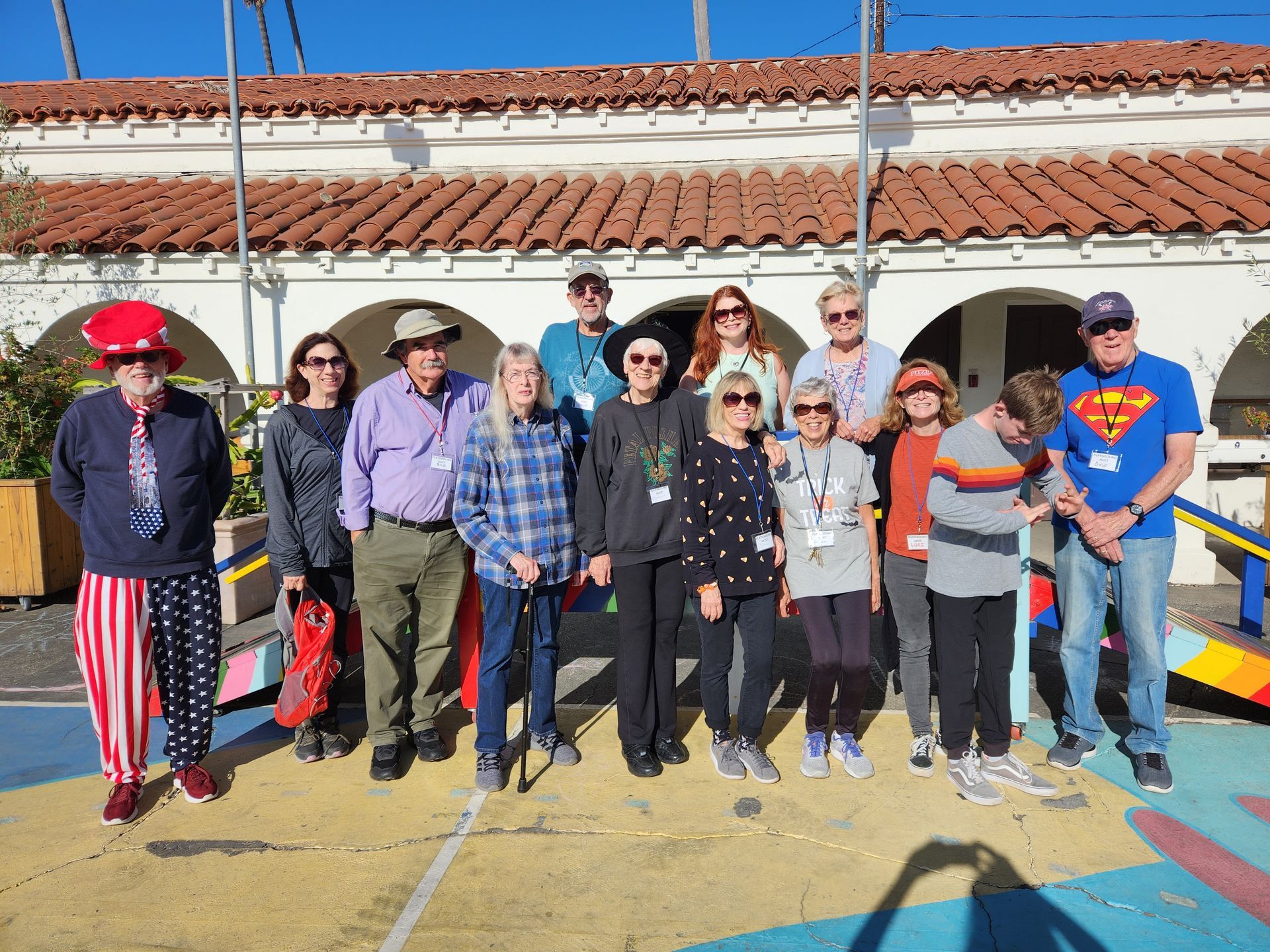 Group of people posing outdoors in front of a building with arches.