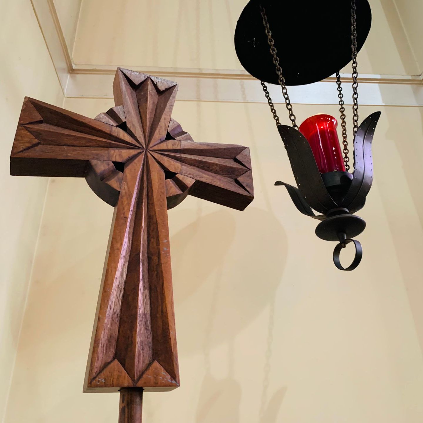 Wooden cross and hanging red candle in a church.