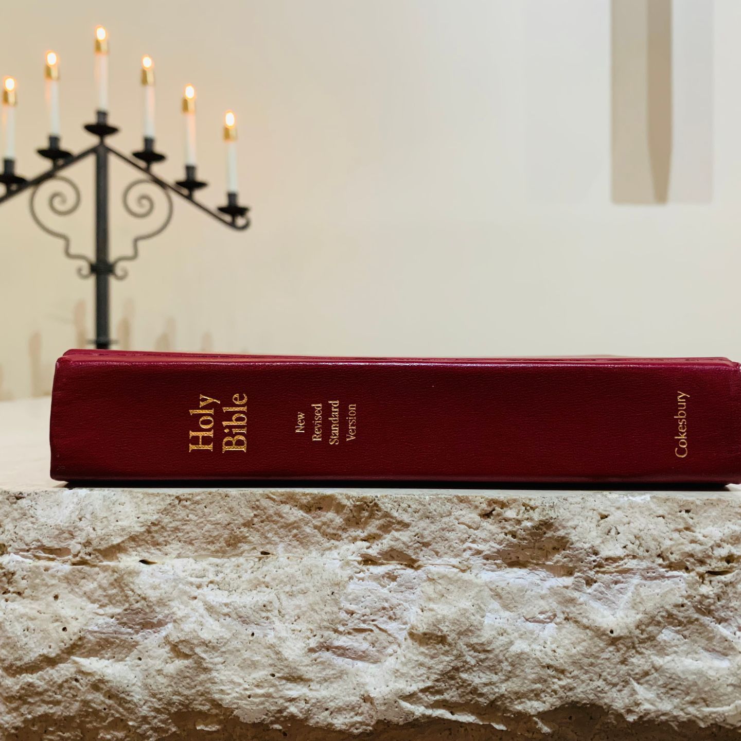 Red Holy Bible on a stone surface with a menorah and candles in the background.