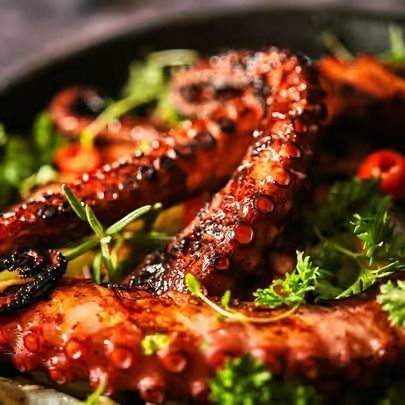 Grilled octopus tentacles garnished with herbs on a dark plate