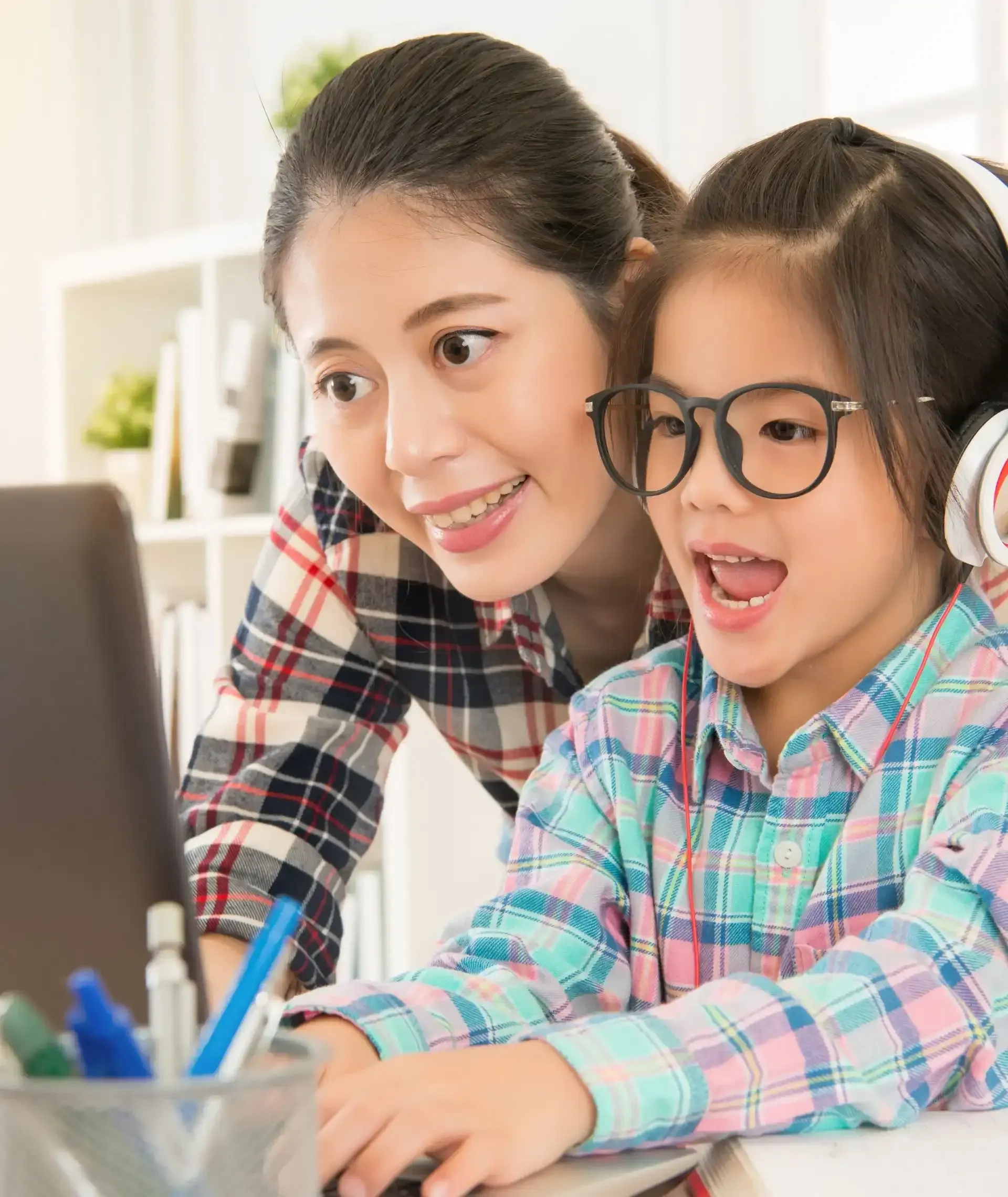 A woman and a little girl are looking at a laptop computer.