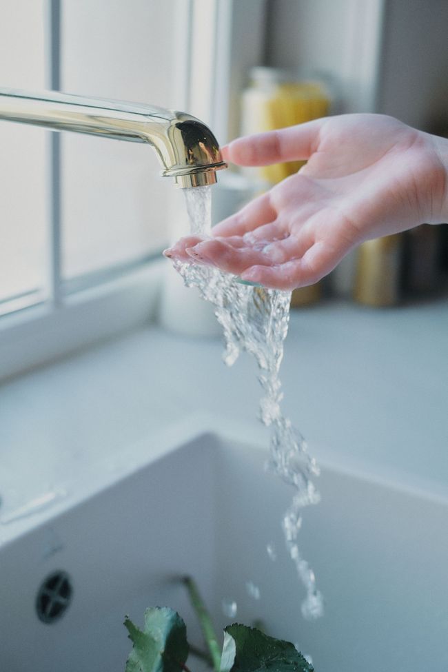 Hand washing under a running faucet in a bathroom sink