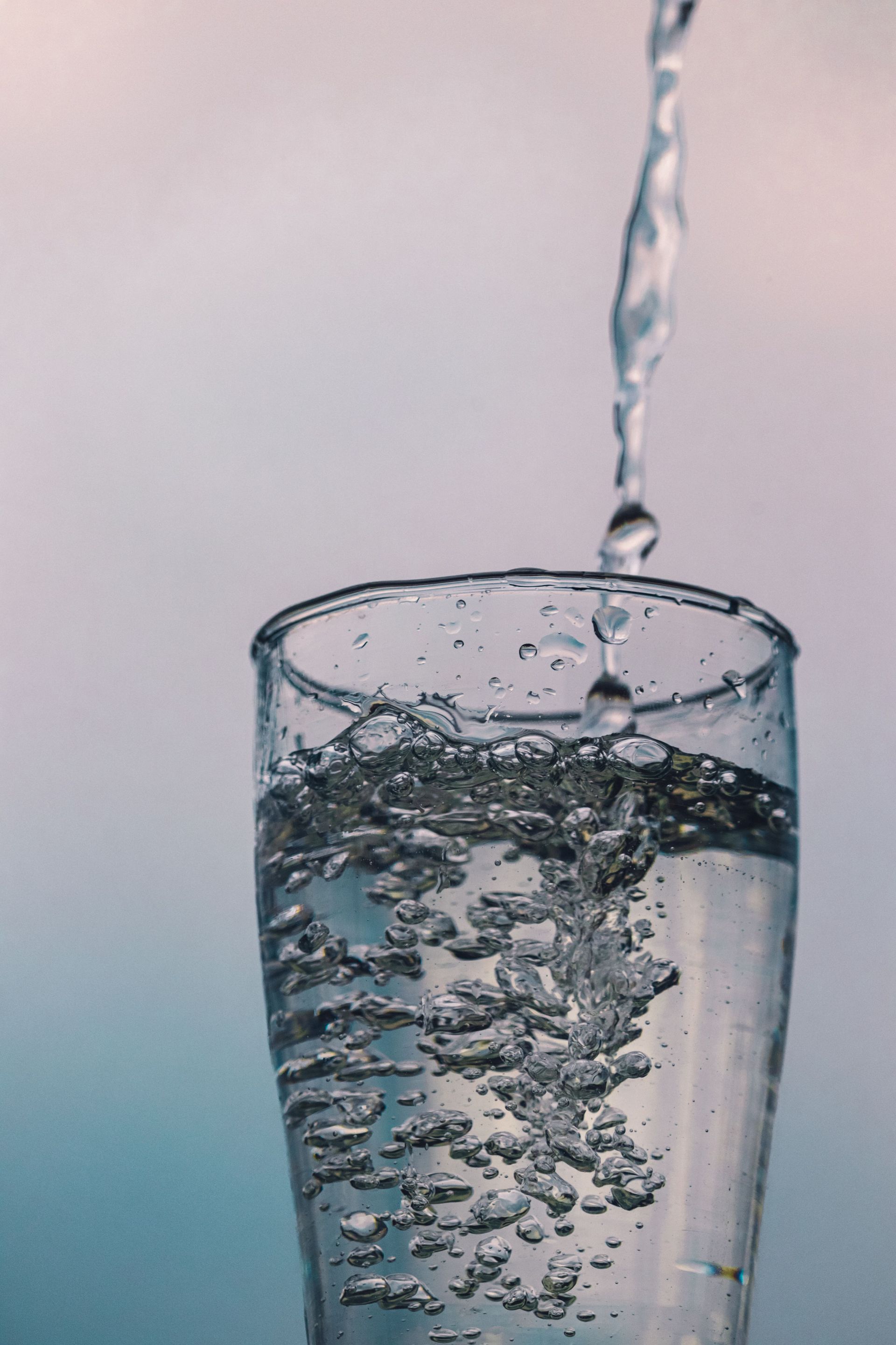 Water pouring into a clear glass, creating bubbles and ripples.