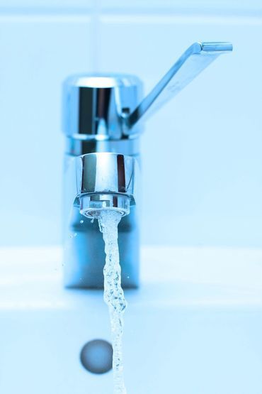 Chrome faucet running water in a light blue bathroom sink