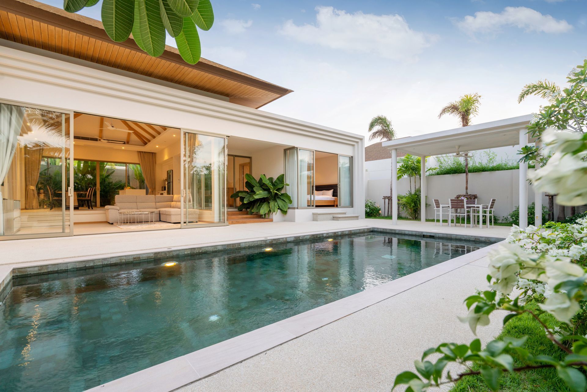 An empty, rectangular swimming pool with deep blue mosaic tiles and built-in steps next to a brick house patio.