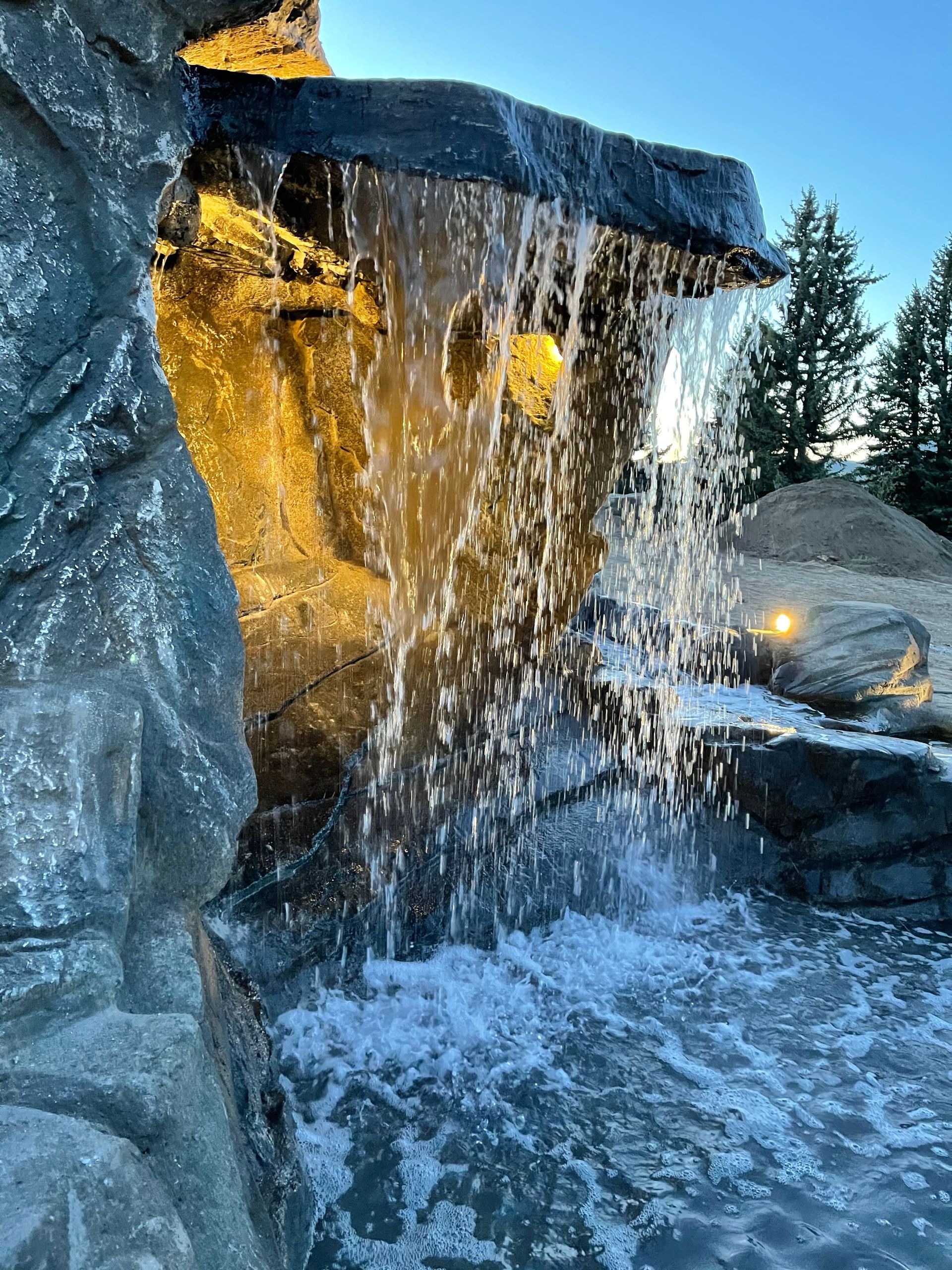 Elite Outdoor Living Solutions is installing a decorative waterfall surrounded by rocks and lighting in Oklahoma City.