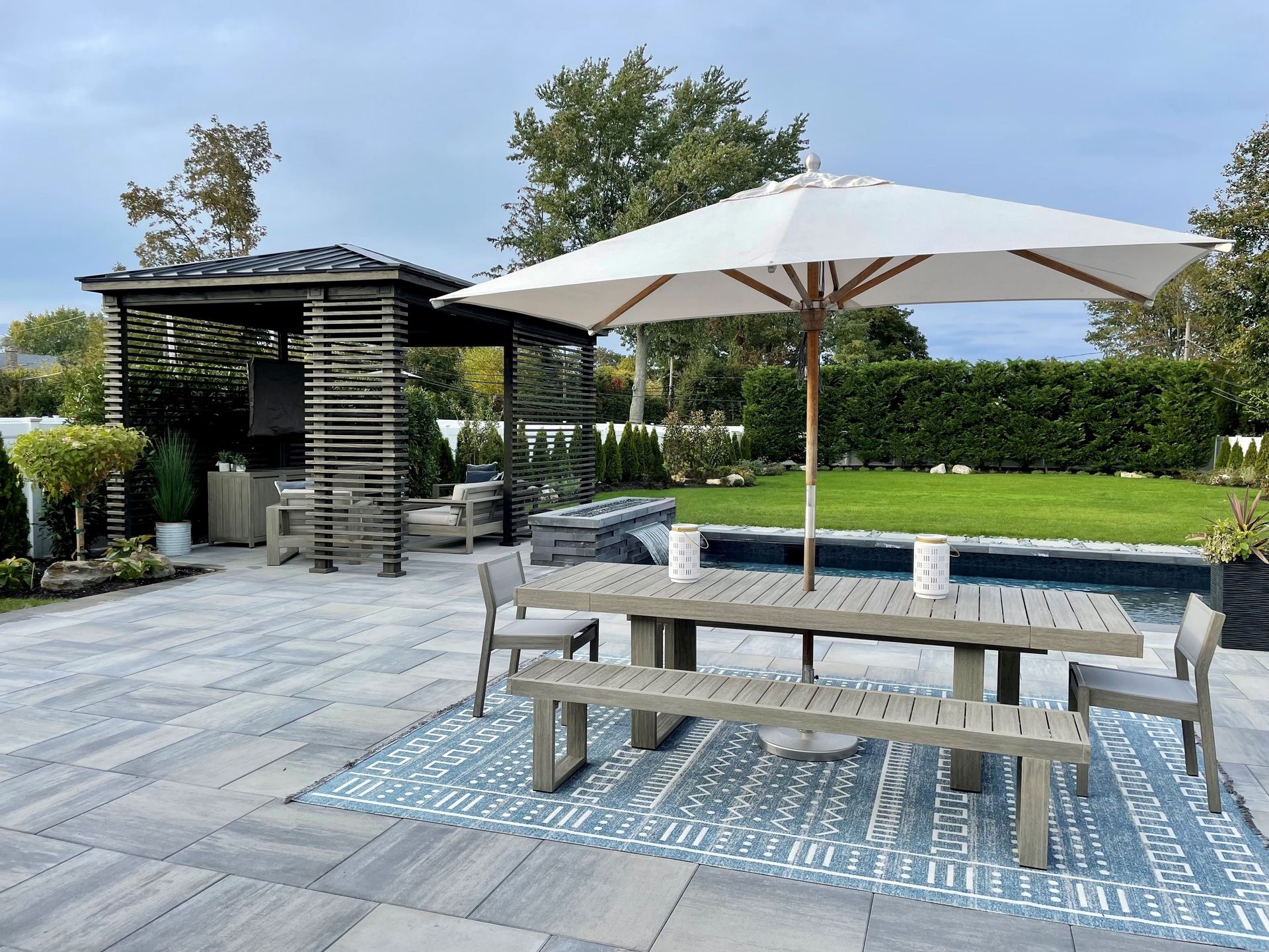 A large white umbrella is sitting on a patio next to a picnic table.