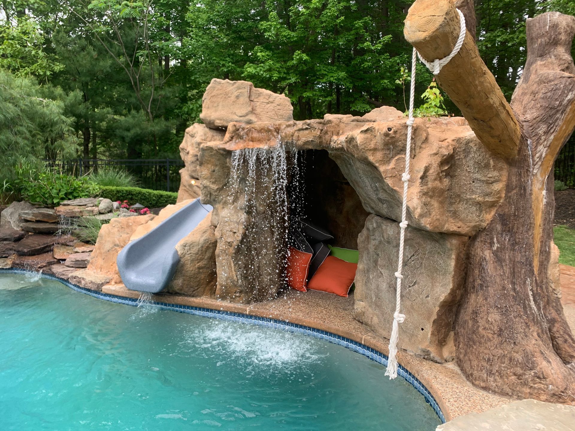 A swimming pool with a waterfall and a slide.