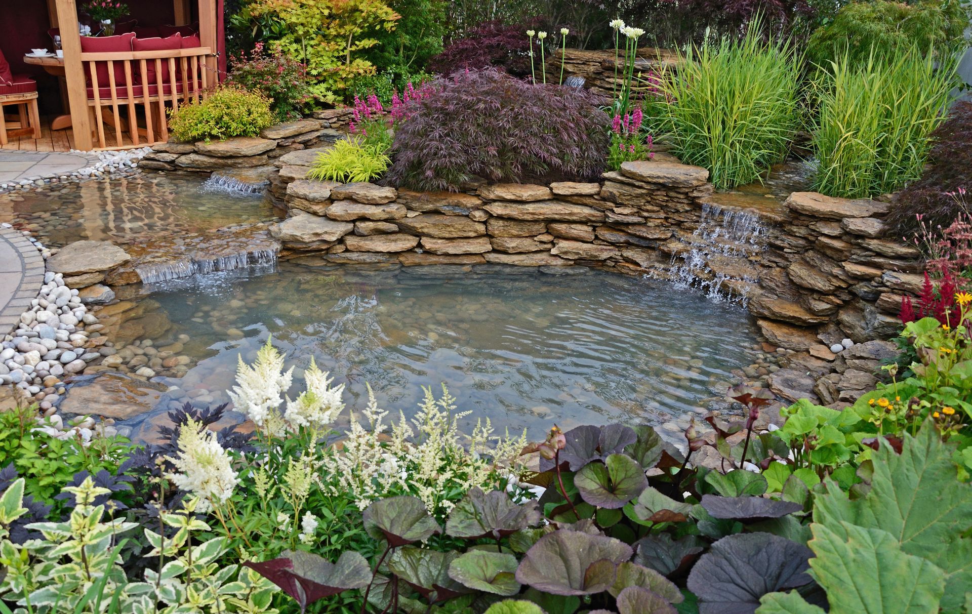 There is a pond with a waterfall in the middle of the garden.
