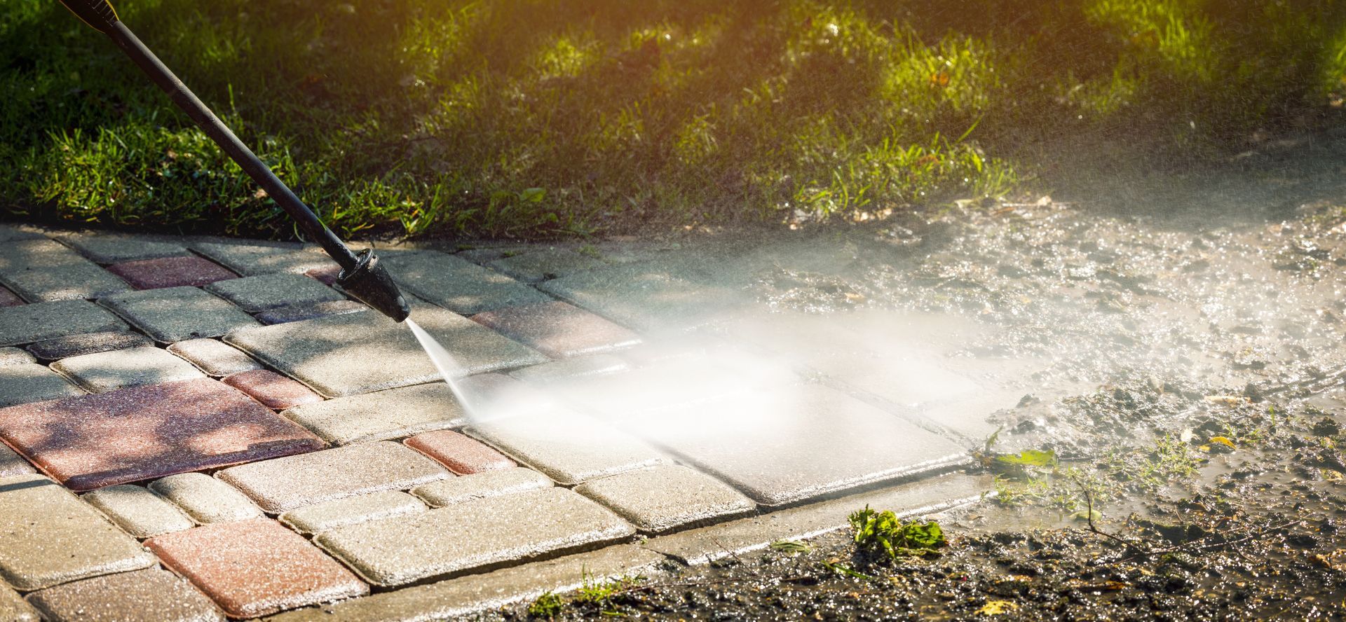 Elite Outdoor Living Solutions pressure washing a filthy concrete driveway surface in Oklahoma City.
