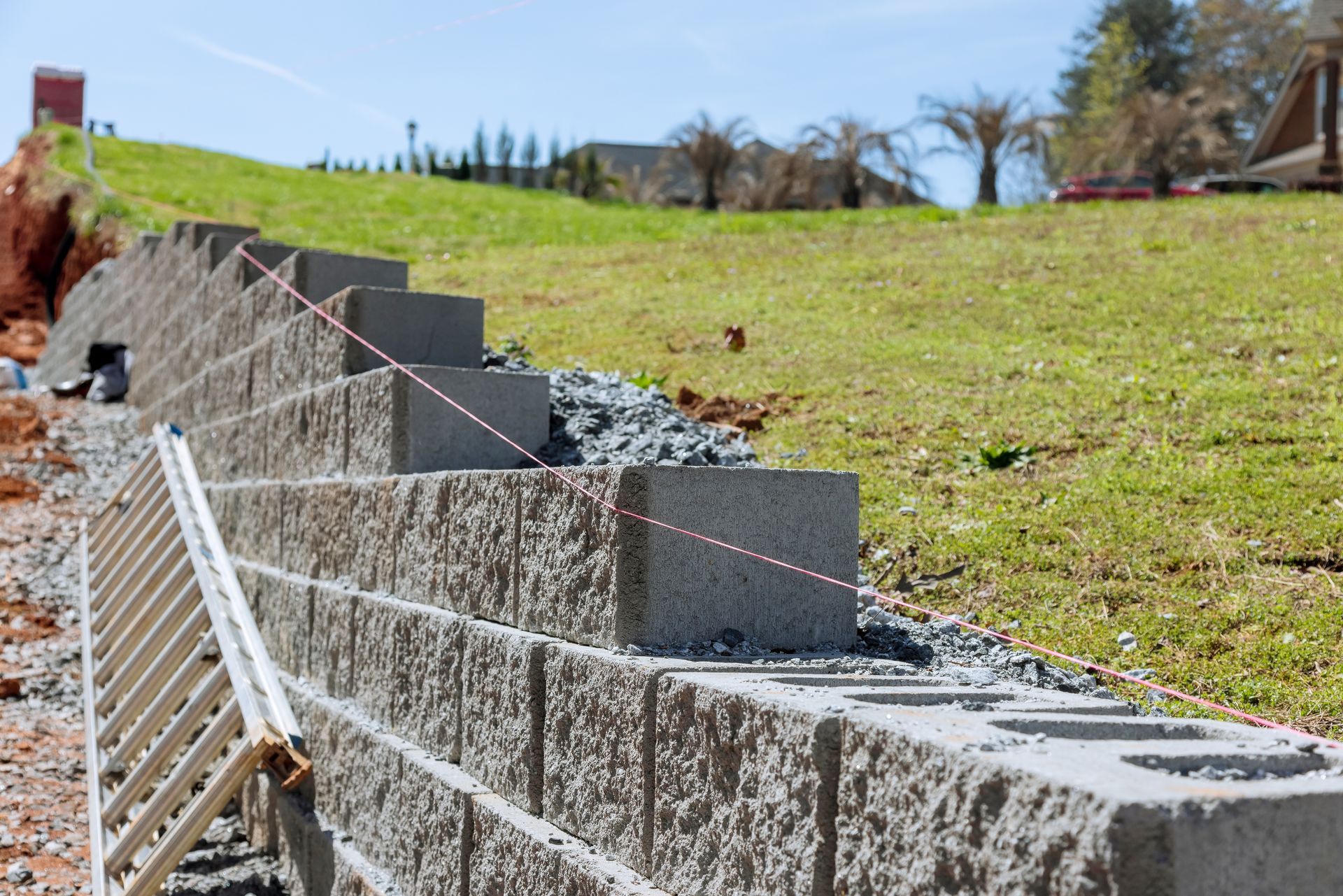 A brick wall is being built on top of a grassy hill.