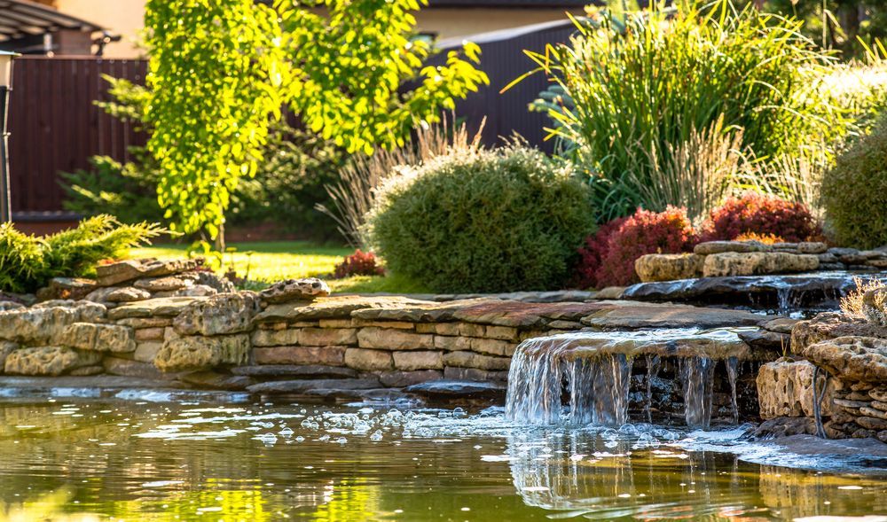 Low-profile pondless waterfall with clean rock edging, installed by Elite Outdoor Living Solutions in Nichols Hills, OK.