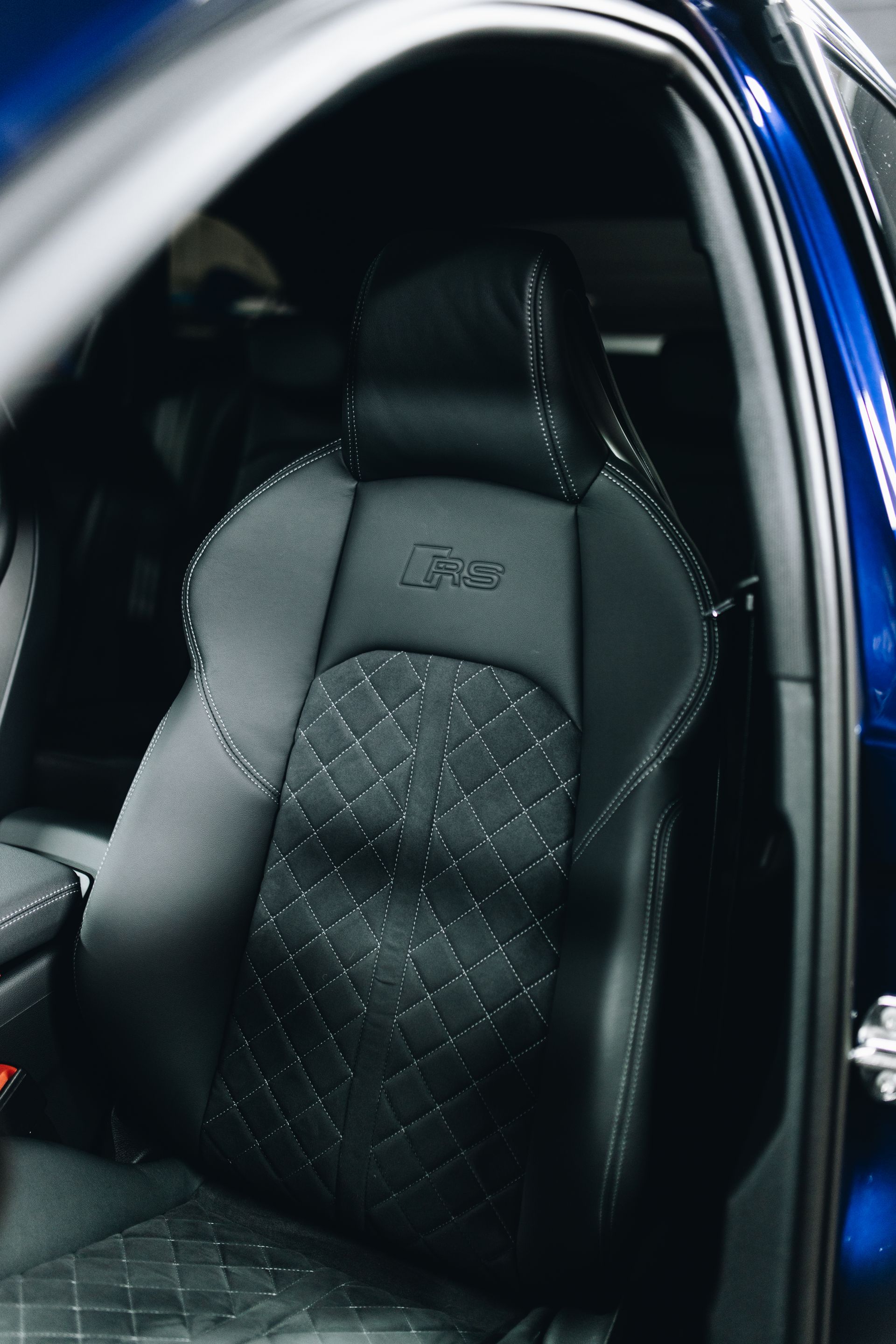Black Quilted Car Seat with Embossed Logo Inside a Vehicle — Straightline Detailing Cairns in Bungalow, QLD