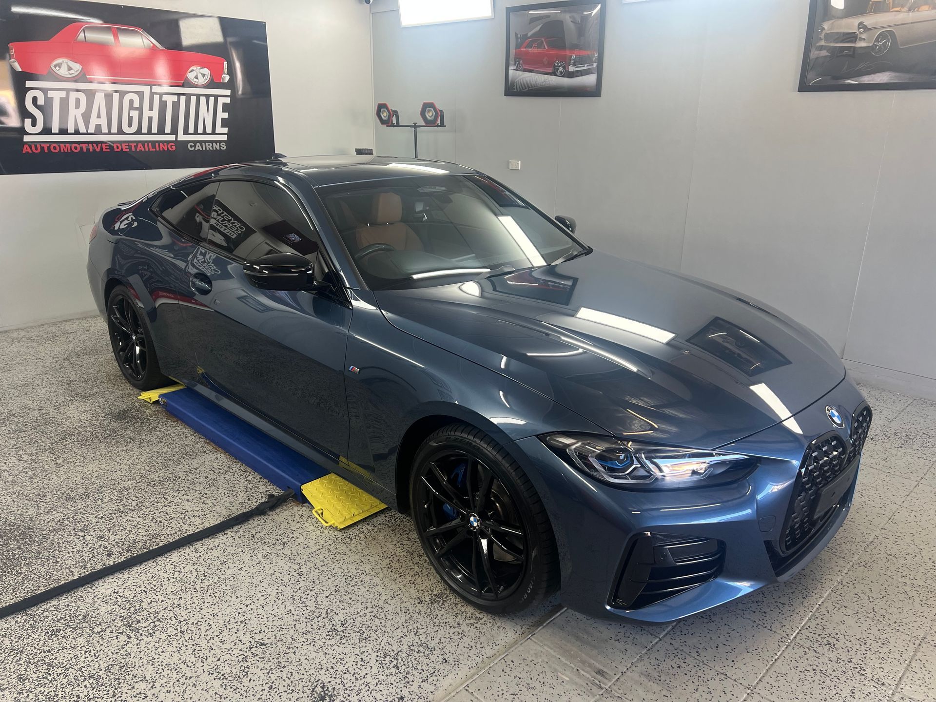 Dark Blue Sports Coupe on A Lift in A Garage — Straightline Detailing Cairns in Bungalow, QLD