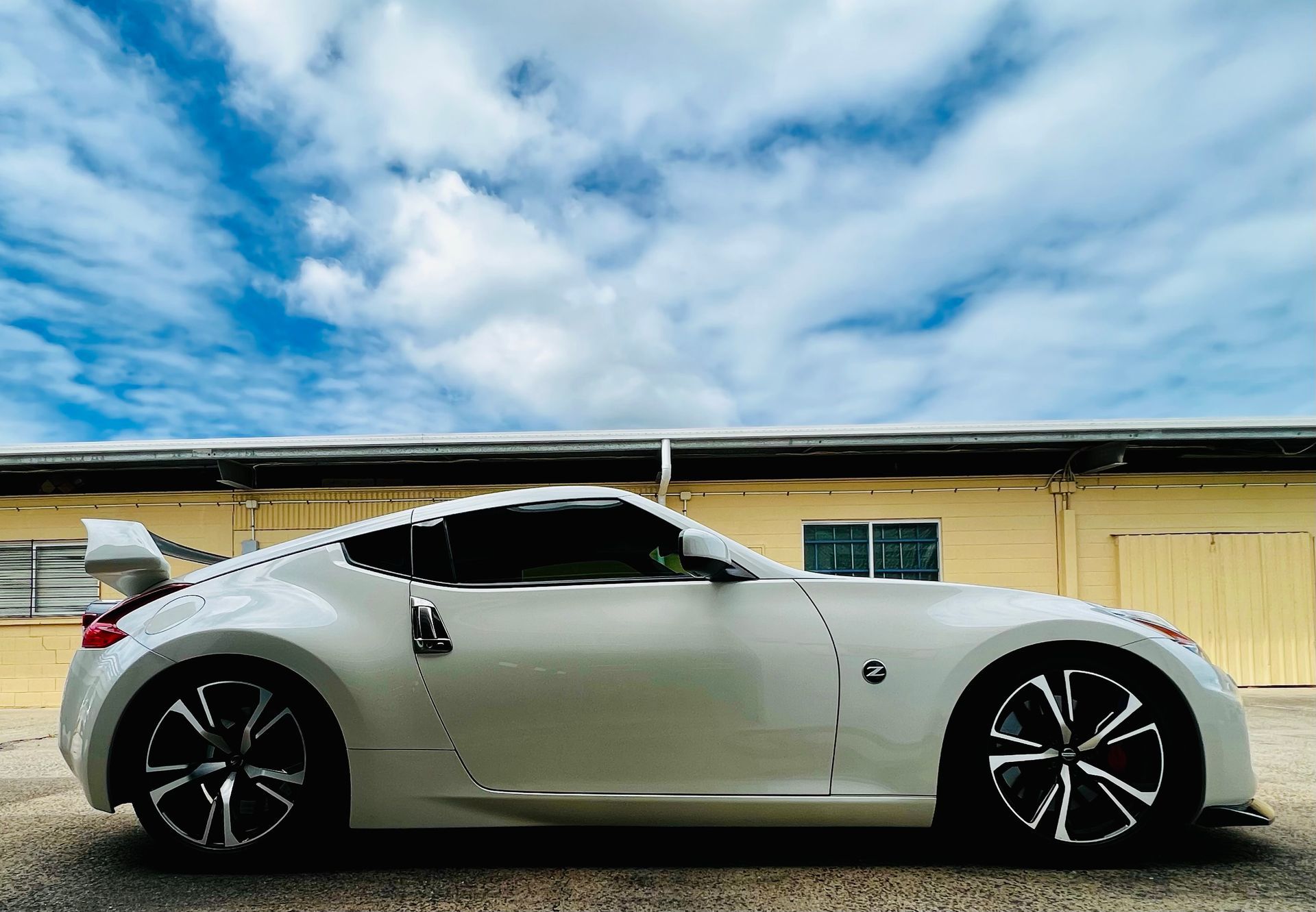 White Sports Coupe Parked Beside a Yellow Building Under a Cloudy Sky — Straightline Detailing Cairns in Bungalow, QLD