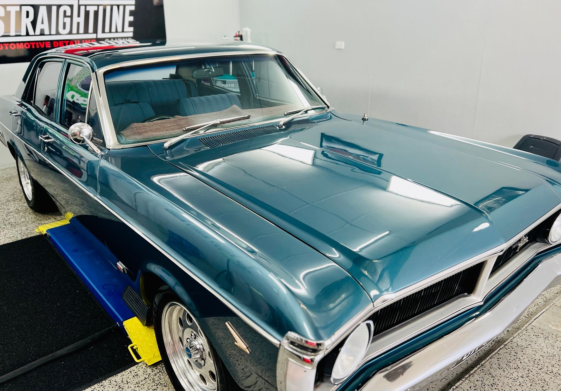Teal Classic Car on A Blue Lift in A Garage — Straightline Detailing Cairns in Bungalow, QLD