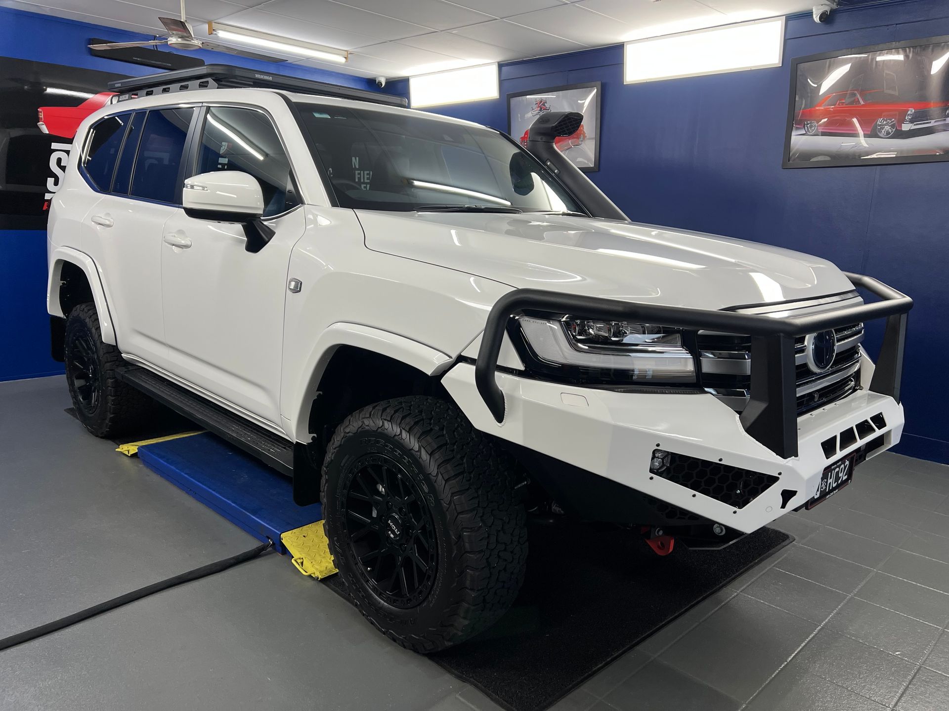 White Suv on A Lift in An Auto Shop, with Black Wheels — Straightline Detailing Cairns in Bungalow, QLD