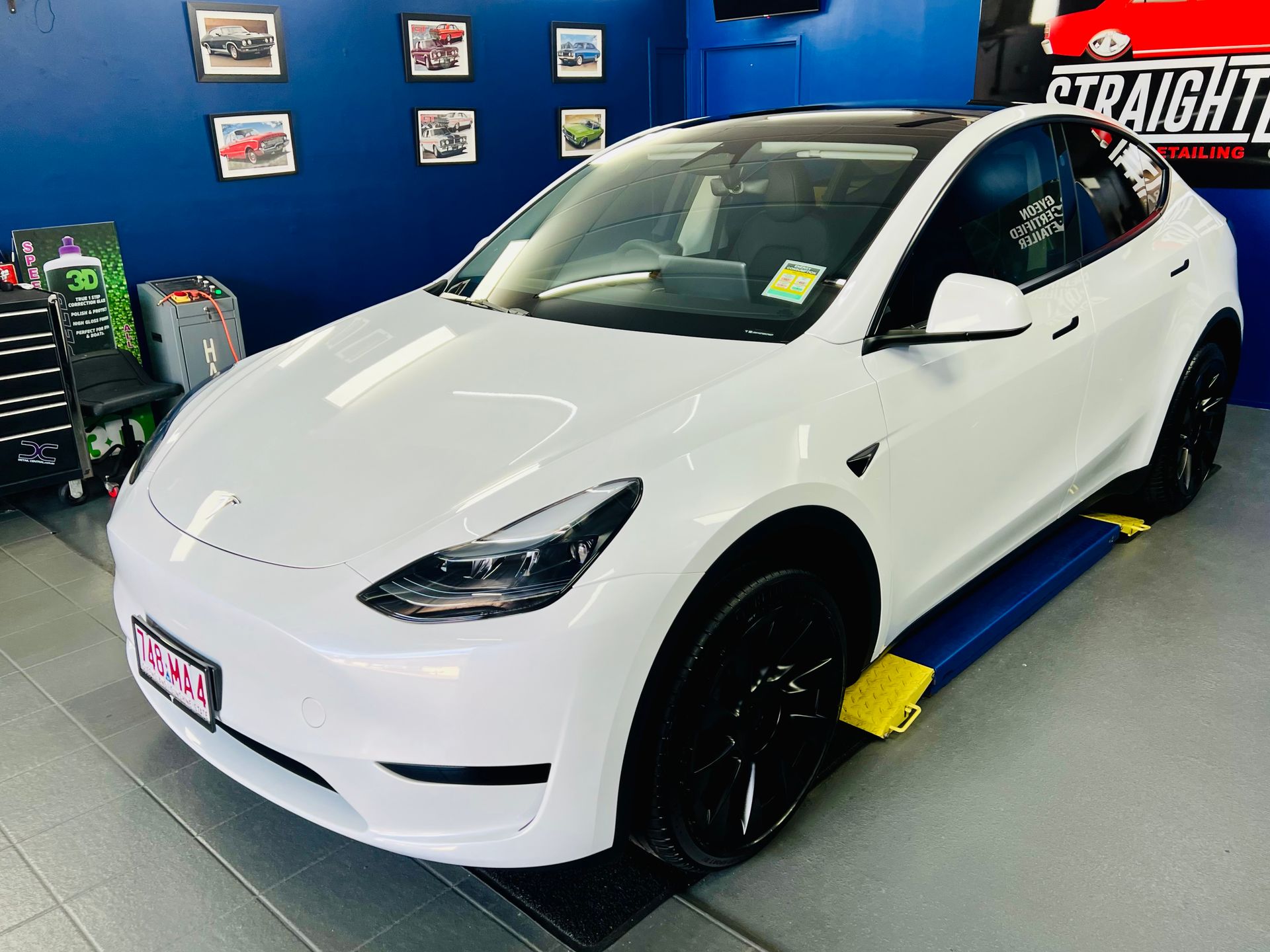 White Tesla SUV in A Blue Auto Shop, Parked on A Yellow Lift Ramp — Straightline Detailing Cairns in Bungalow, QLD