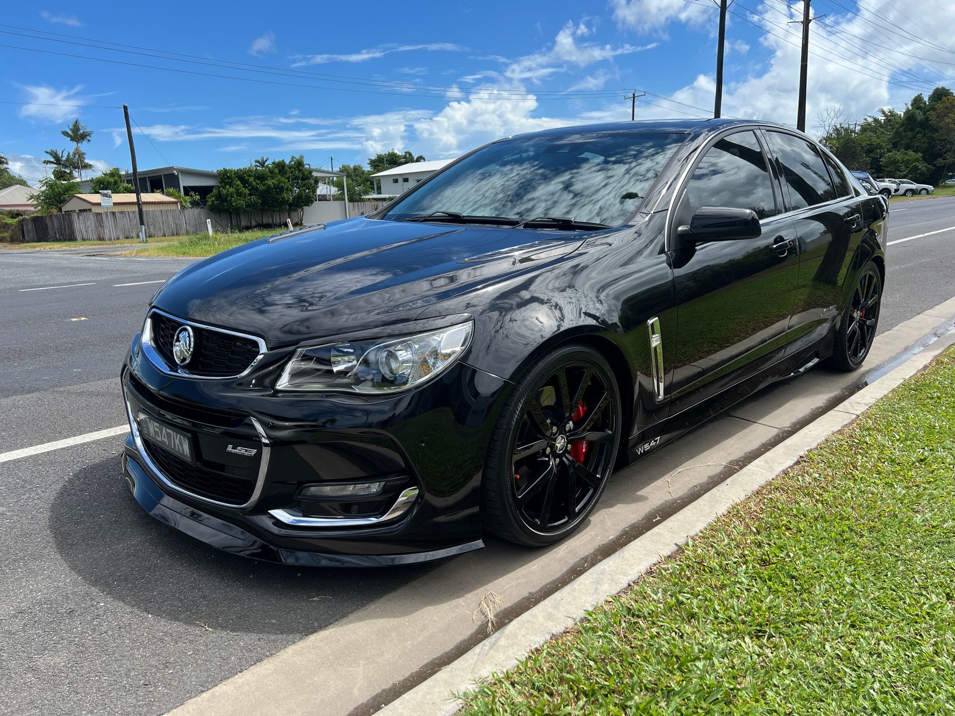 Black Sedan Parked by A Curb on A Sunny Street Under a Blue Sky — Straightline Detailing Cairns in Bungalow, QLD