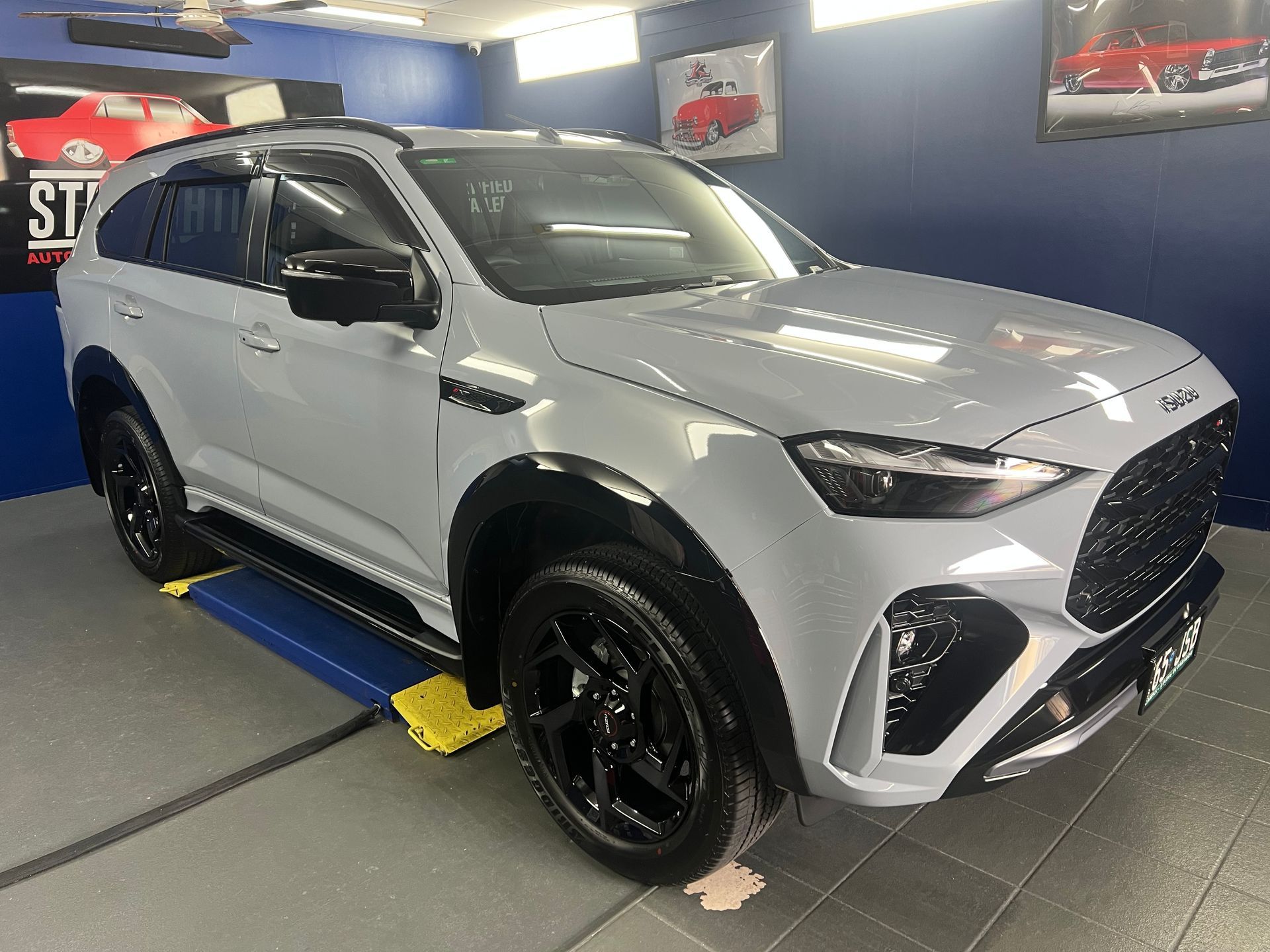 White SUV In an Auto Shop, Shown on A Lift with Black Wheels — Straightline Detailing Cairns in Bungalow, QLD