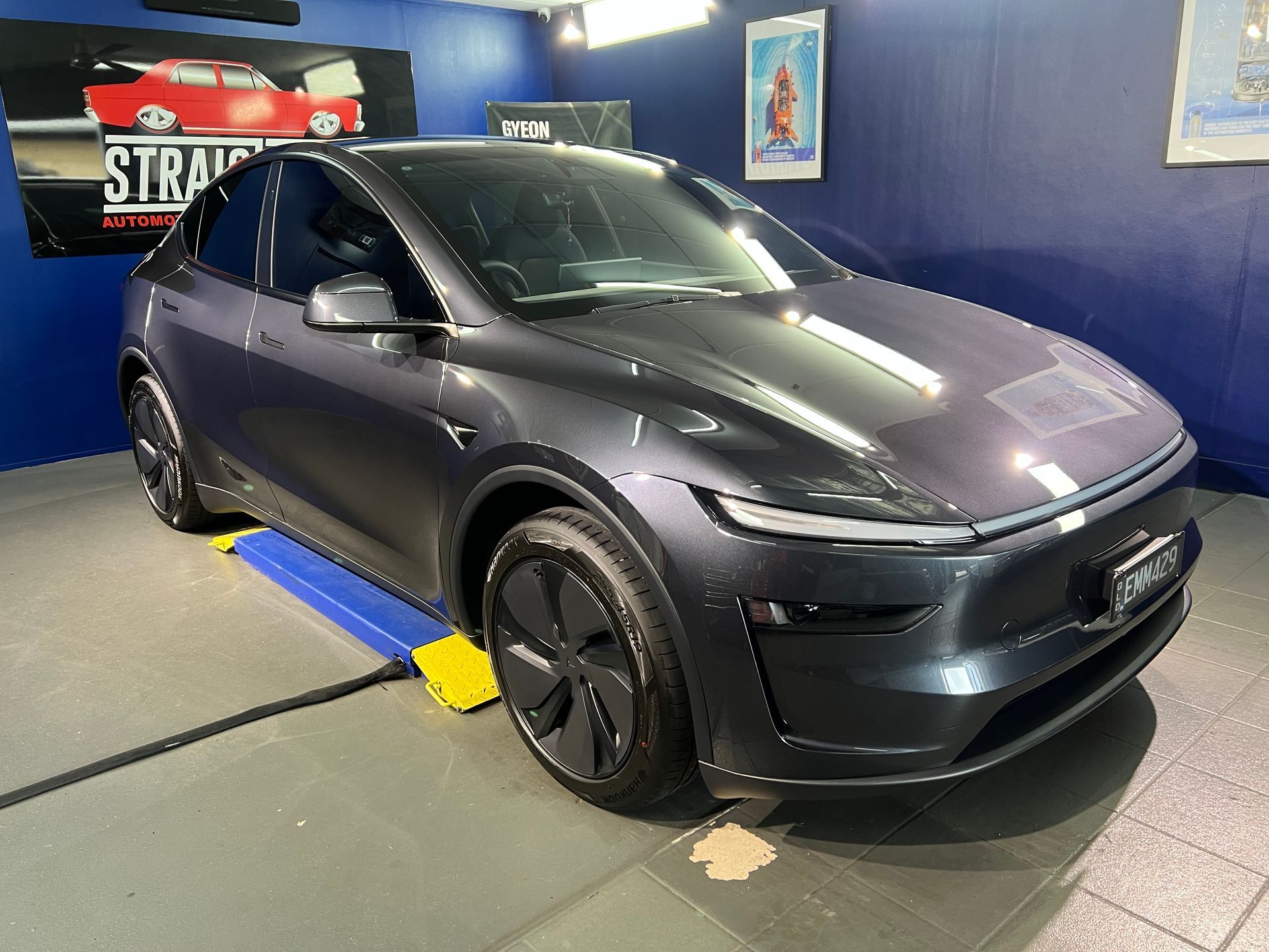 Dark Gray Tesla on A Showroom Floor with Blue Walls — Straightline Detailing Cairns in Bungalow, QLD