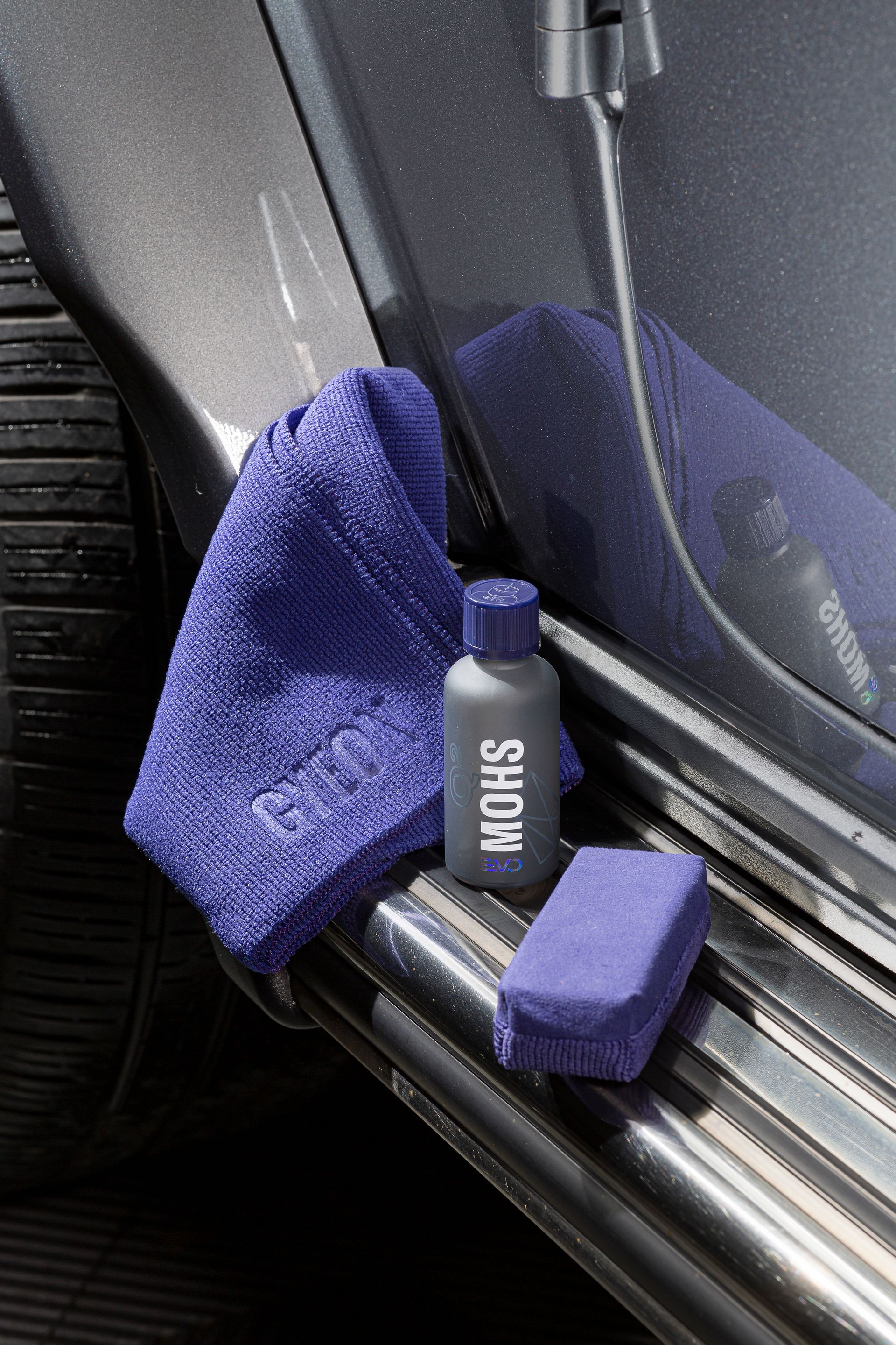 Blue Cleaning Cloth and Spray Bottle Tucked Beside a Car Door Sill — Straightline Detailing Cairns in Bungalow, QLD