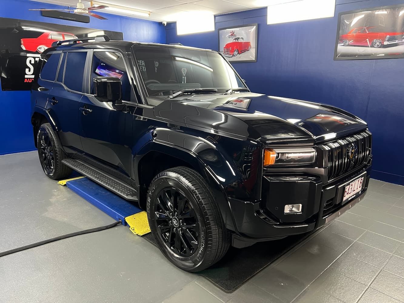 Black SUV Parked Indoors in A Blue-Walled Showroom — Straightline Detailing Cairns in Bungalow, QLD