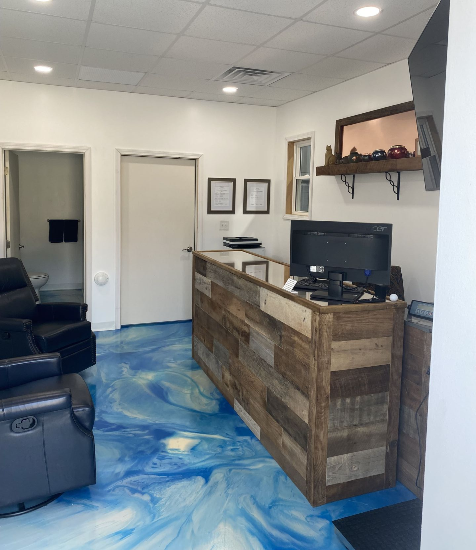 Reception area with a wood-paneled counter, blue epoxy floor, and two doors.