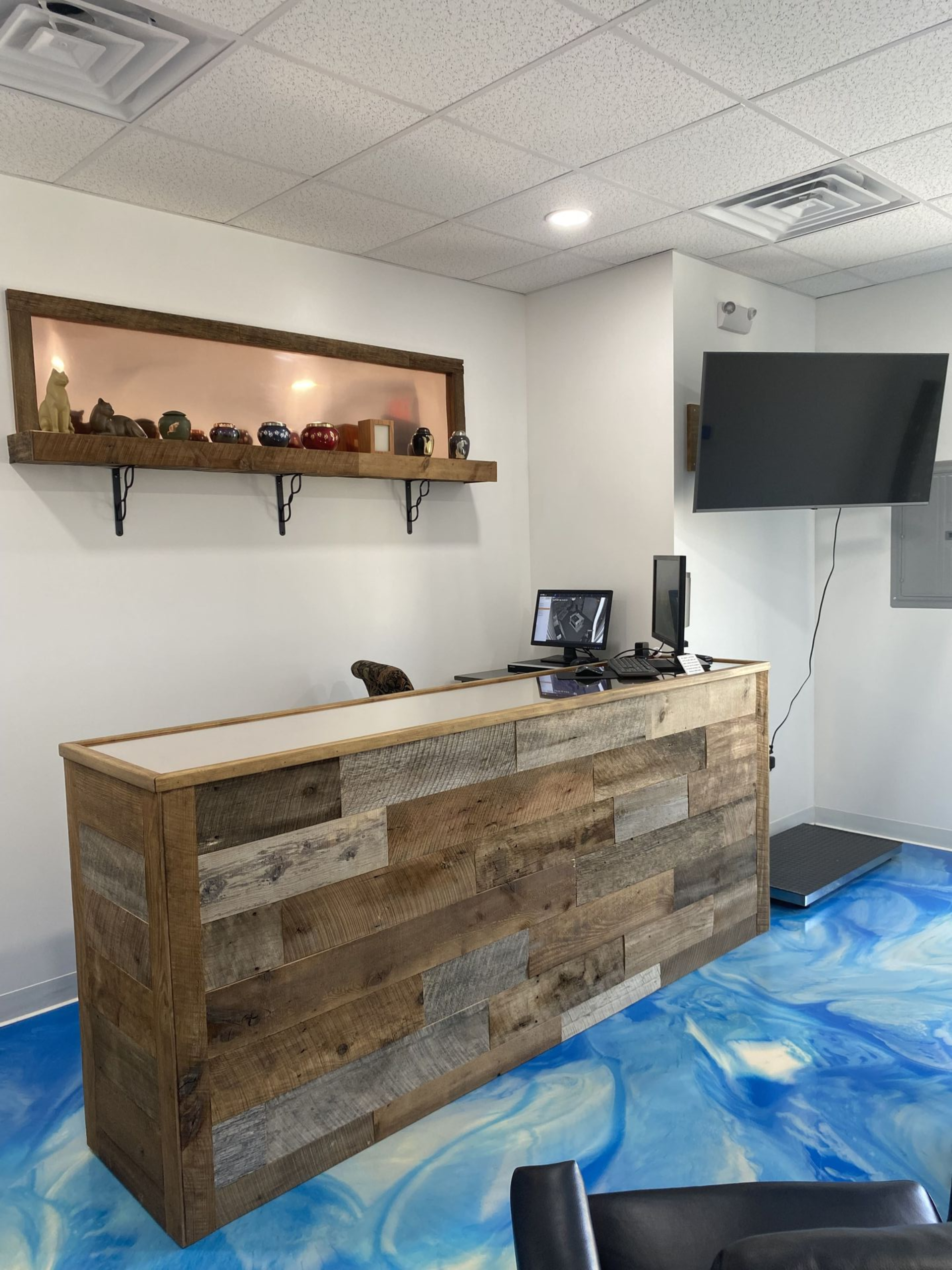 Reception area with a rustic wood front desk and blue and white floor.