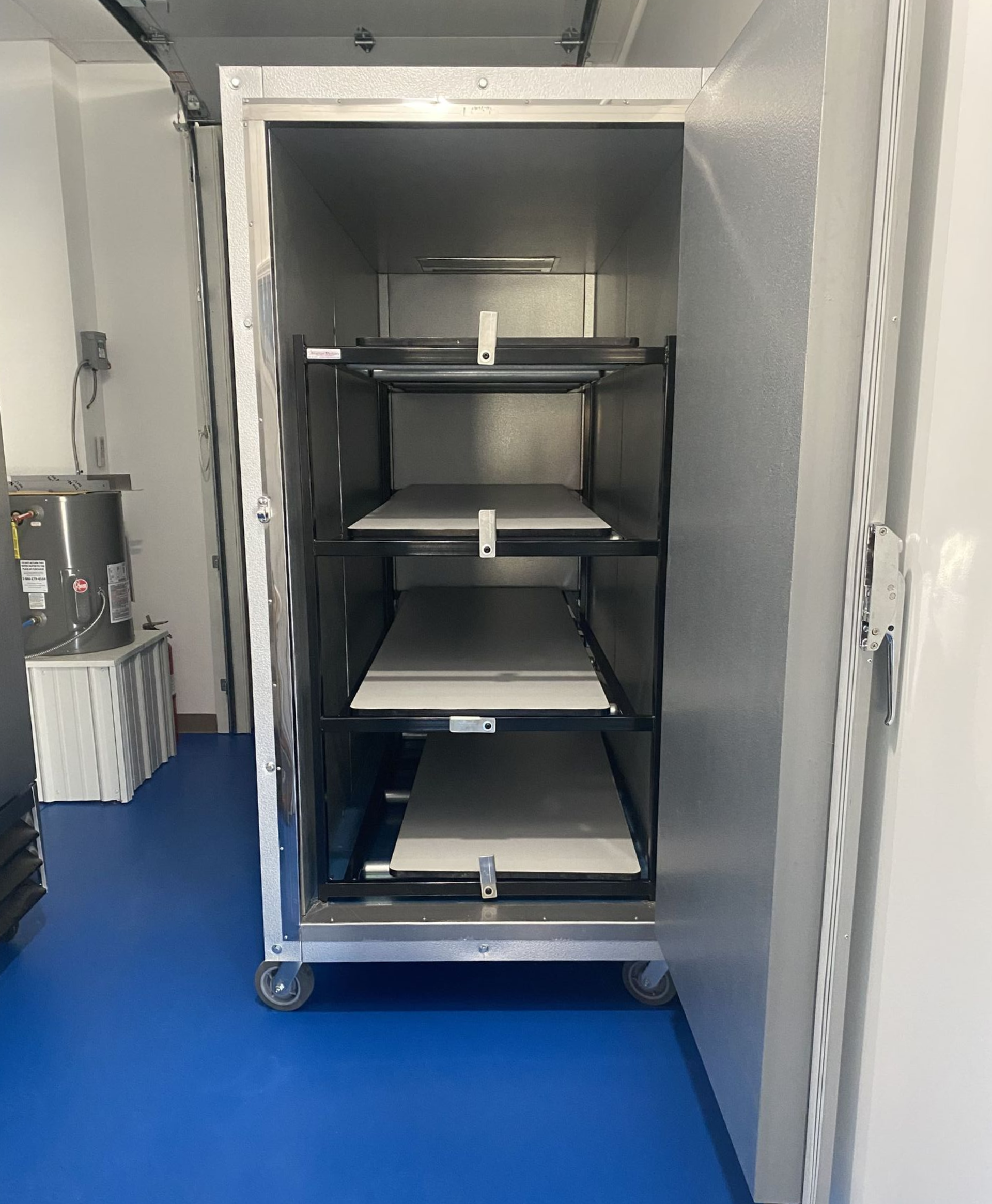 Open, rolling, stainless steel storage cabinet with three shelves, on blue floor.