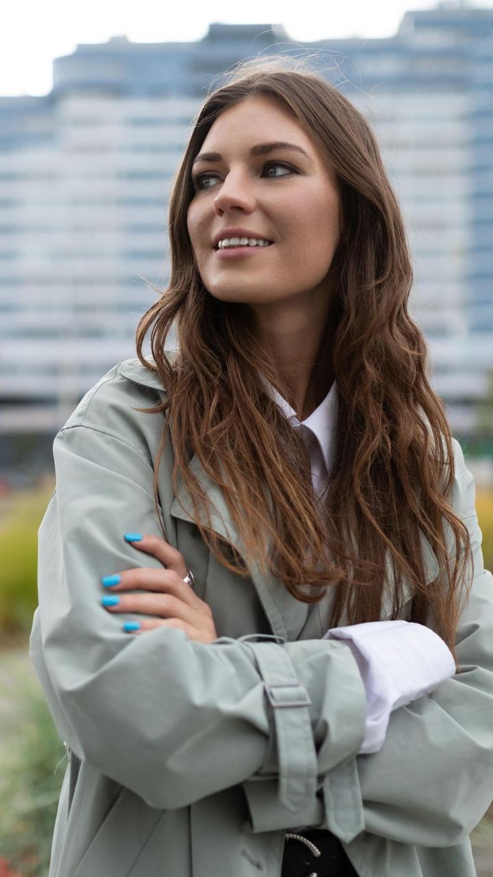 A confident woman with blue nails is smiling with her arms crossed after working with Erin Freeman