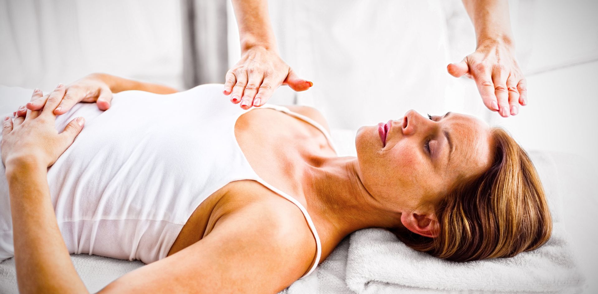 a woman is laying on a bed getting a reiki treatment .
