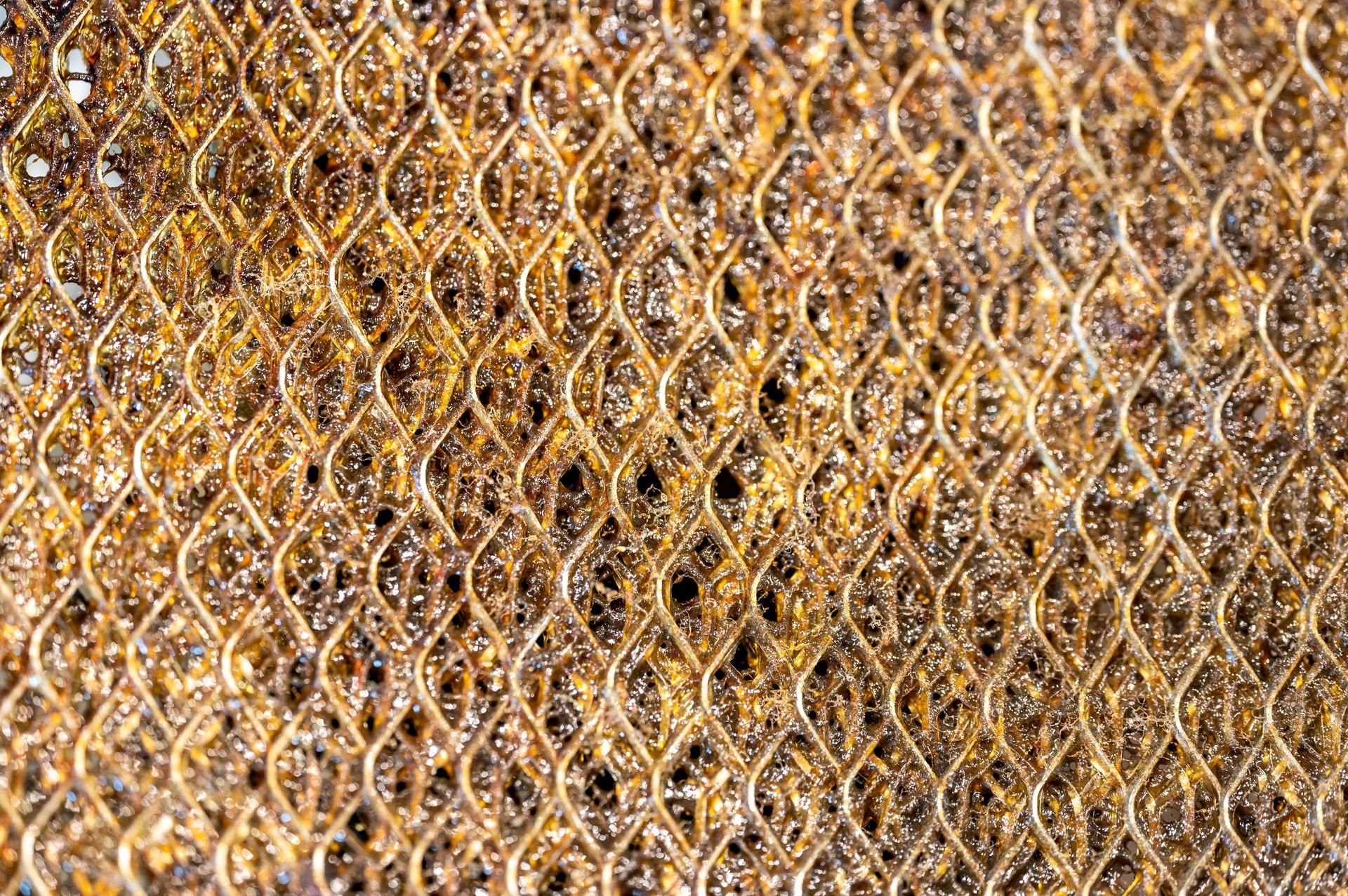 Golden woven metal mesh pattern with repeating diamond shapes and textured sparkle