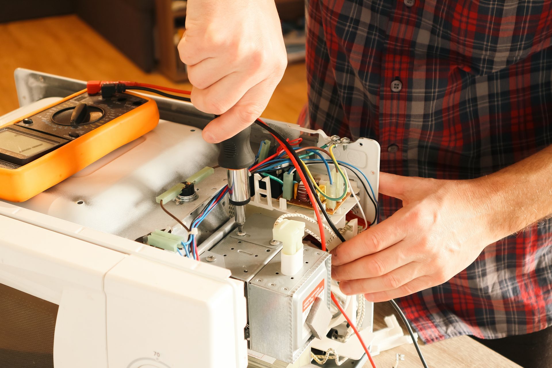Person using a screwdriver to repair an open electronic device on a workbench
