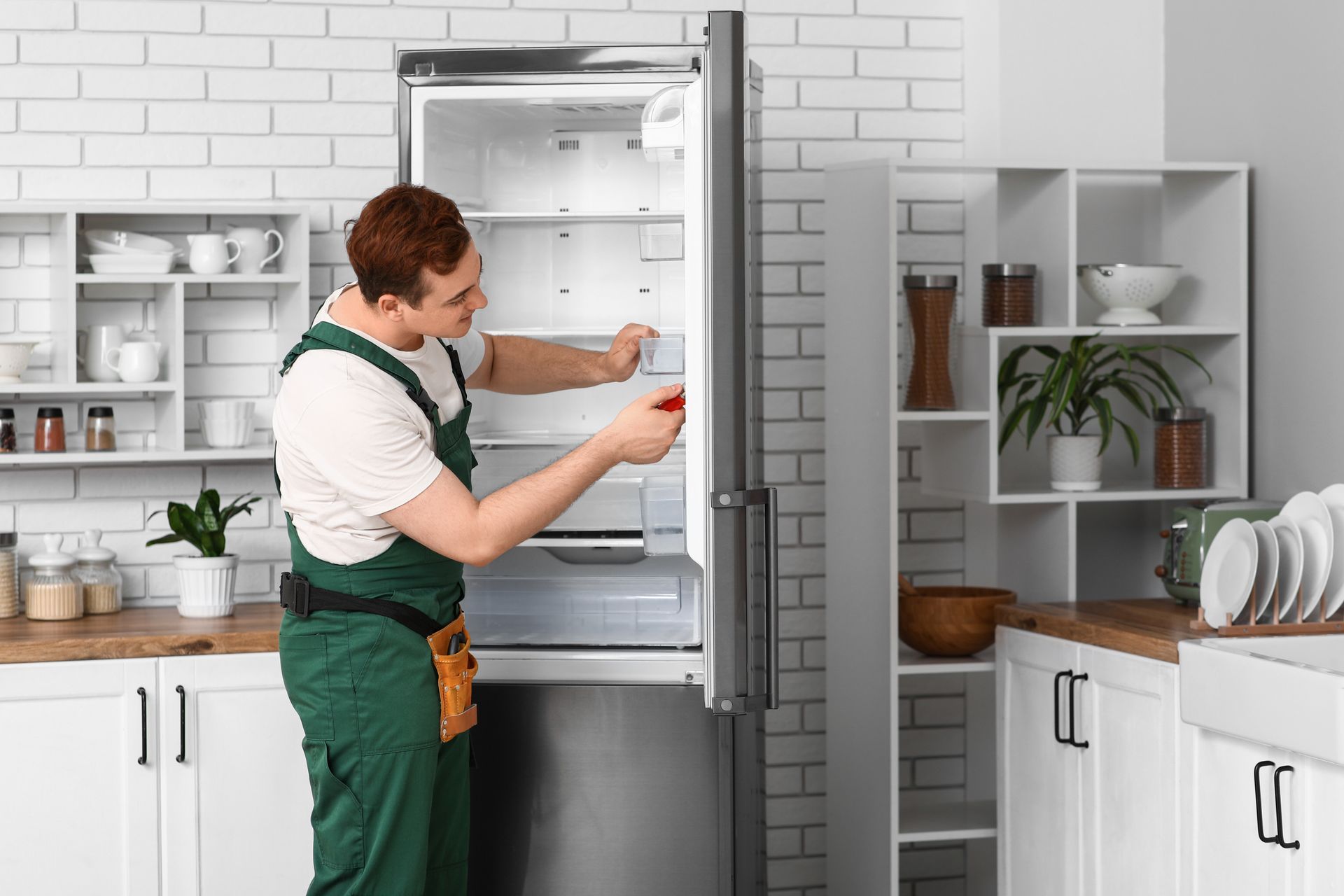 Person placing a red item in an open refrigerator in a bright kitchen