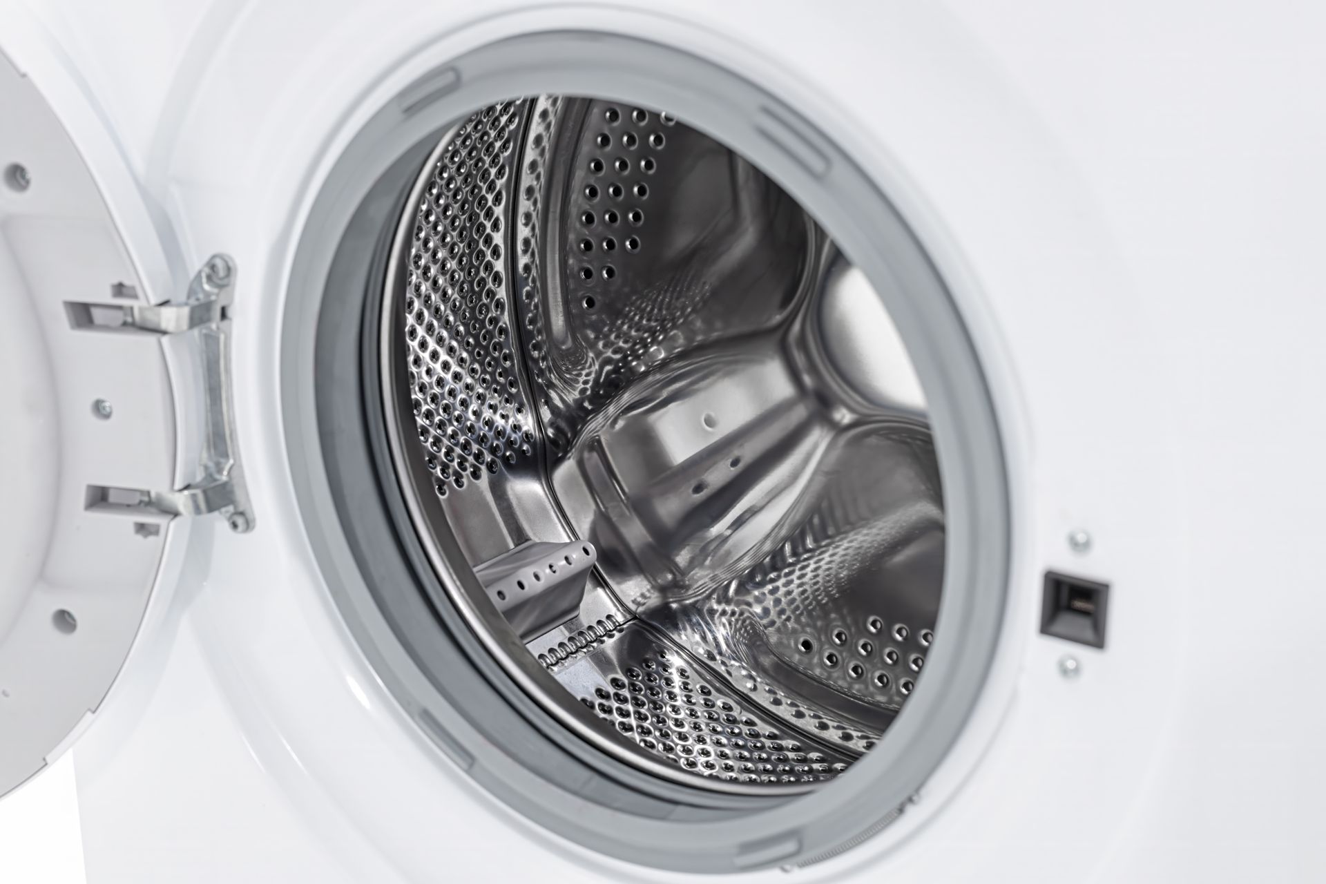 Open front-loading washing machine drum with stainless steel interior and white door frame