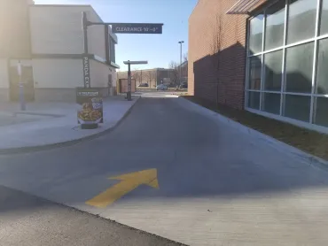 Alleyway between brick buildings with a large yellow directional arrow painted on the pavement.