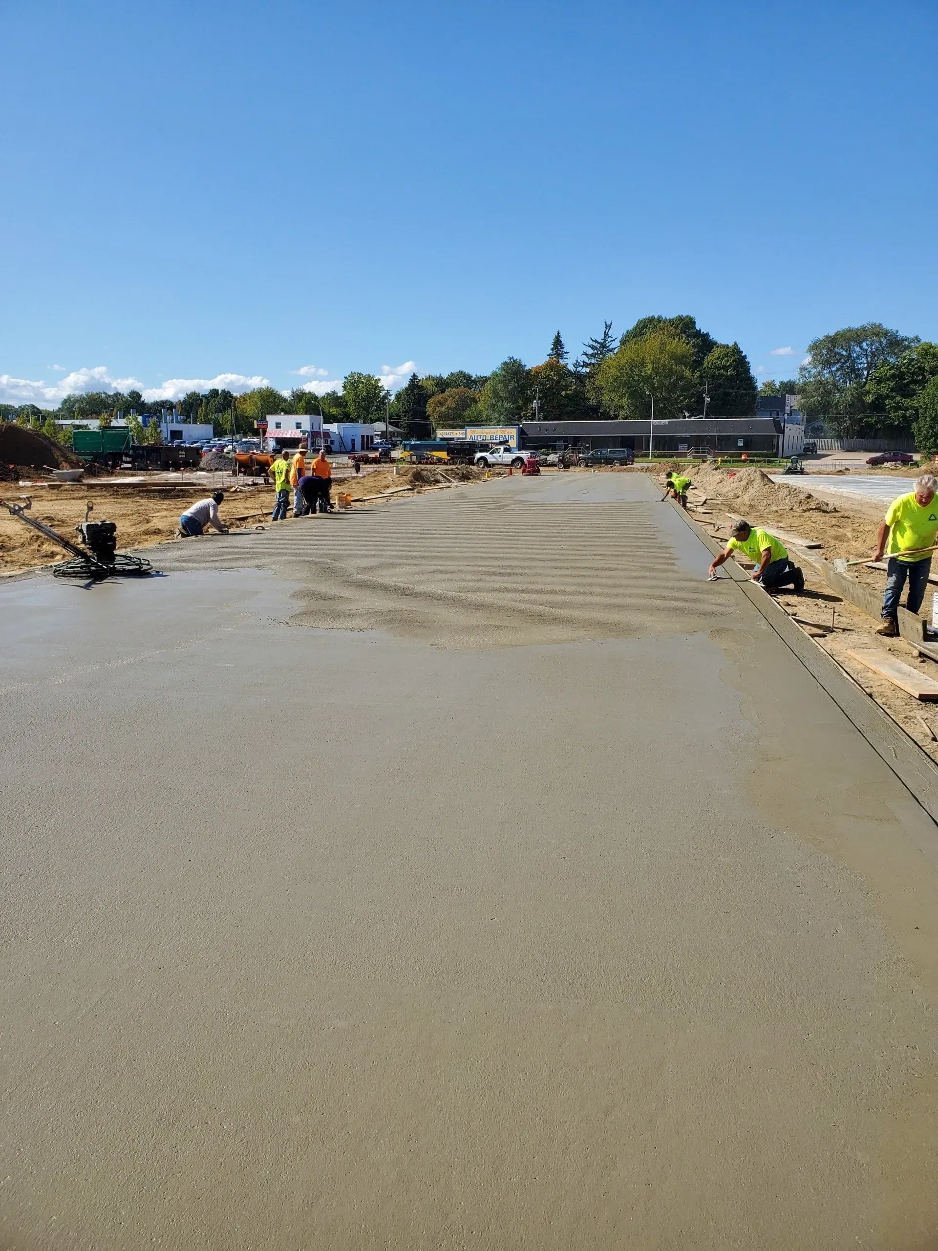 Fresh concrete slab being poured at a construction site under a clear blue sky