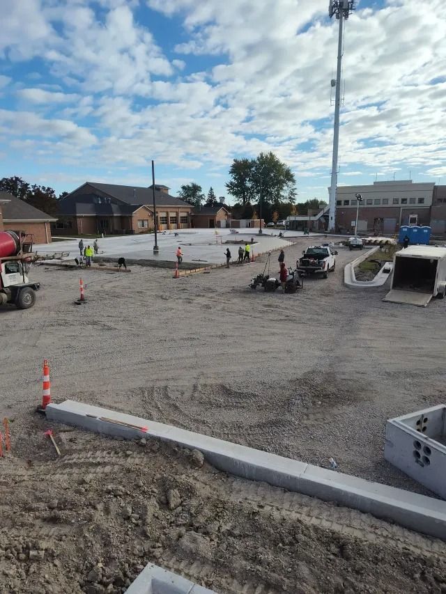 Construction site with gravel lot, orange cones, parked cars, and a cloudy sky. Construction site with gravel lot, orange cones, parked cars, and a cloudy sky.