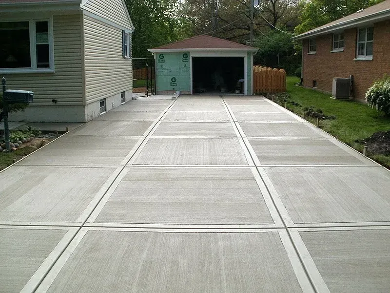 Freshly poured concrete driveway leading to a detached garage beside a house and fenced yard Freshly poured concrete driveway leading to a detached garage beside a house and fenced yard