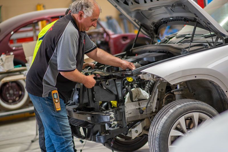 A man is working on the engine of a car in a garage.
