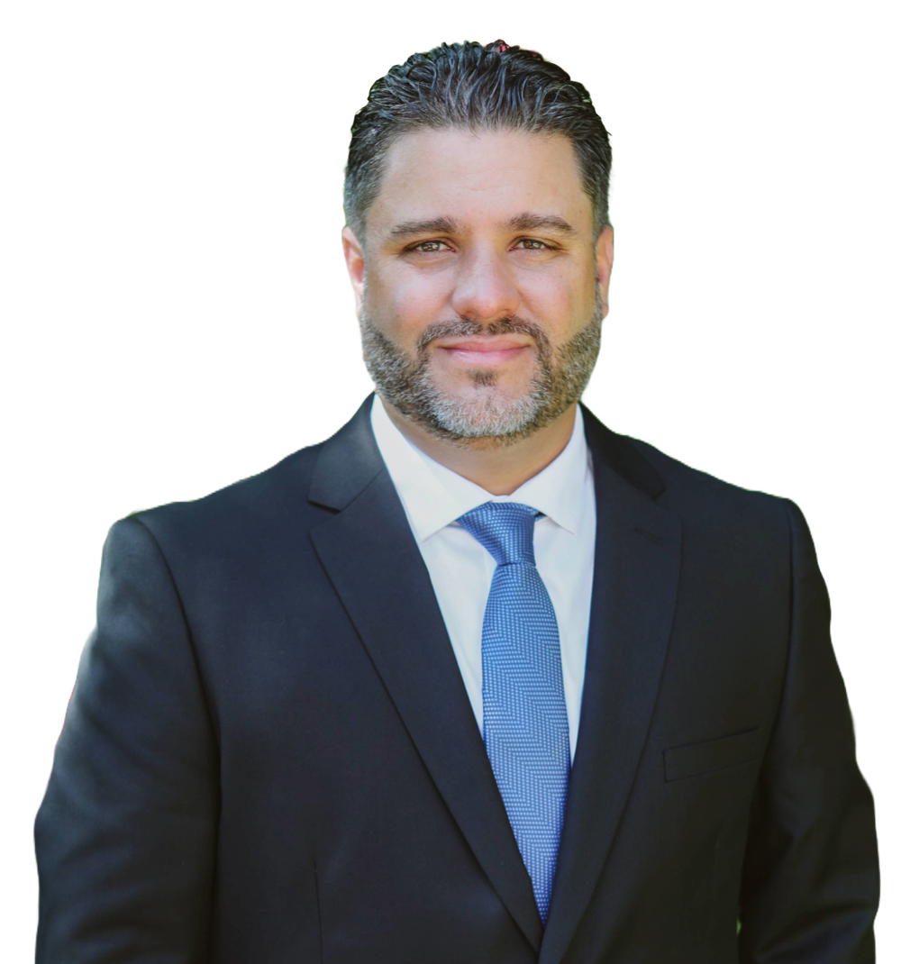 A man in a suit and tie is standing in front of a white background.