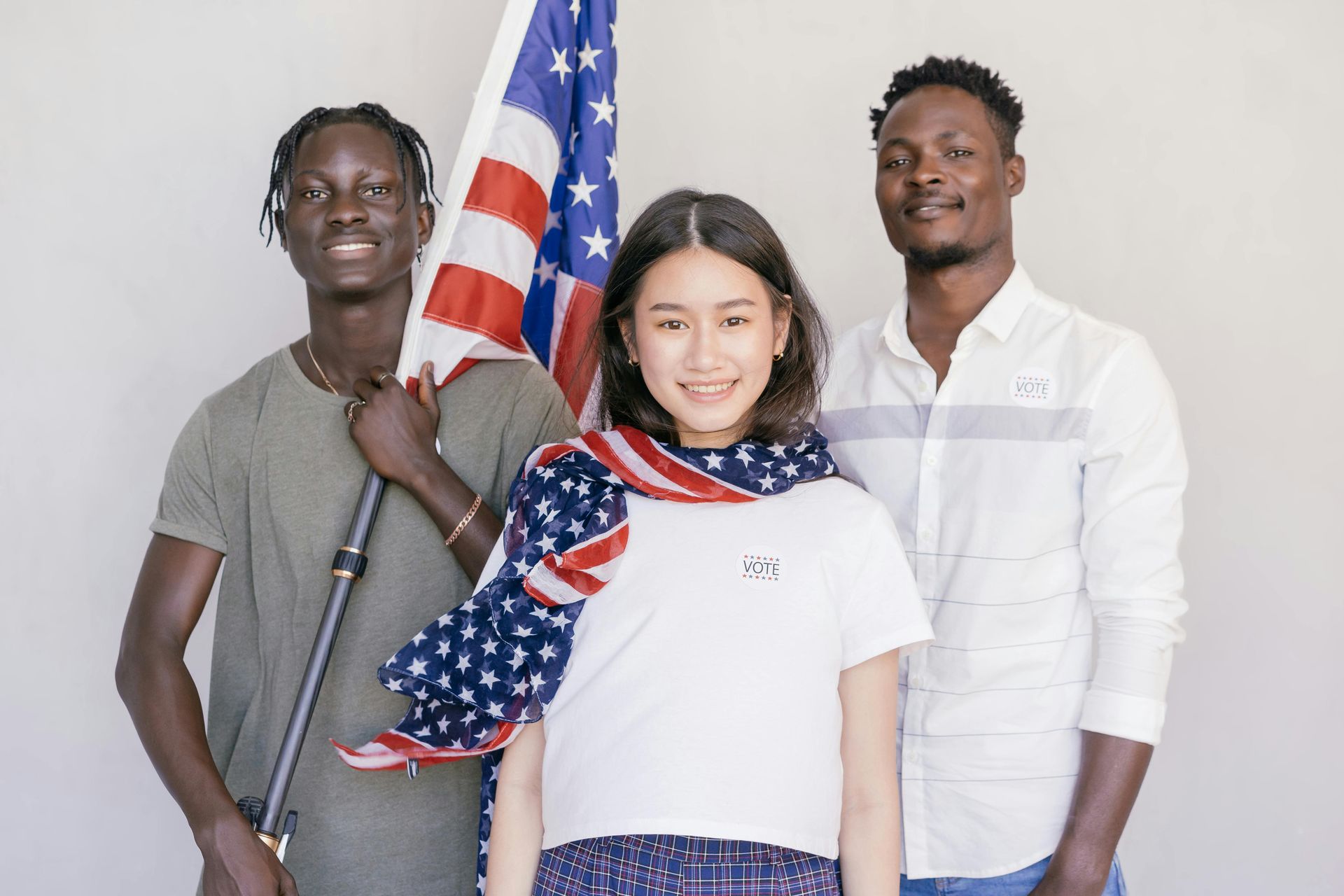 Three people are standing next to each other holding an american flag.