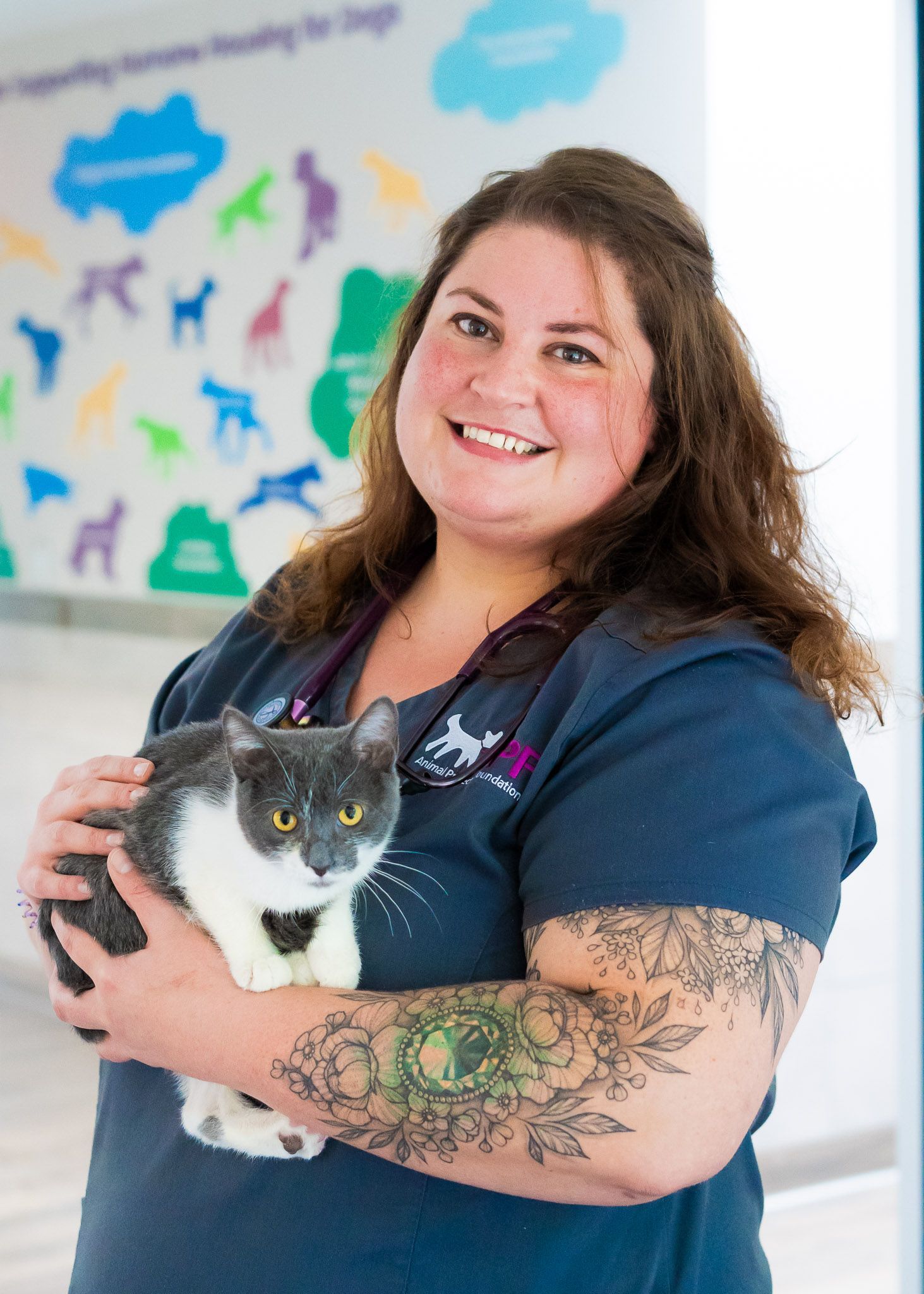 A woman is holding a cat in her arms and smiling.