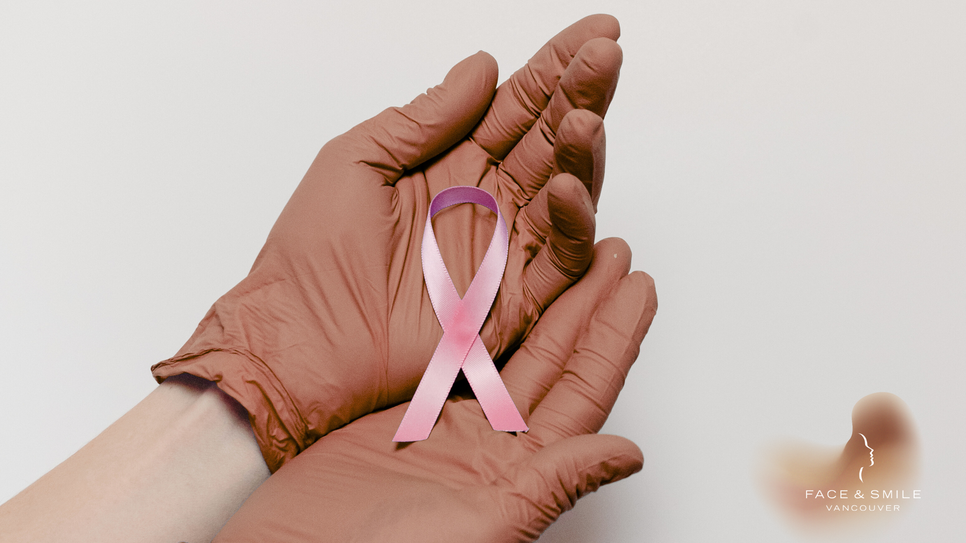 A person wearing gloves is holding a pink ribbon in their hands.