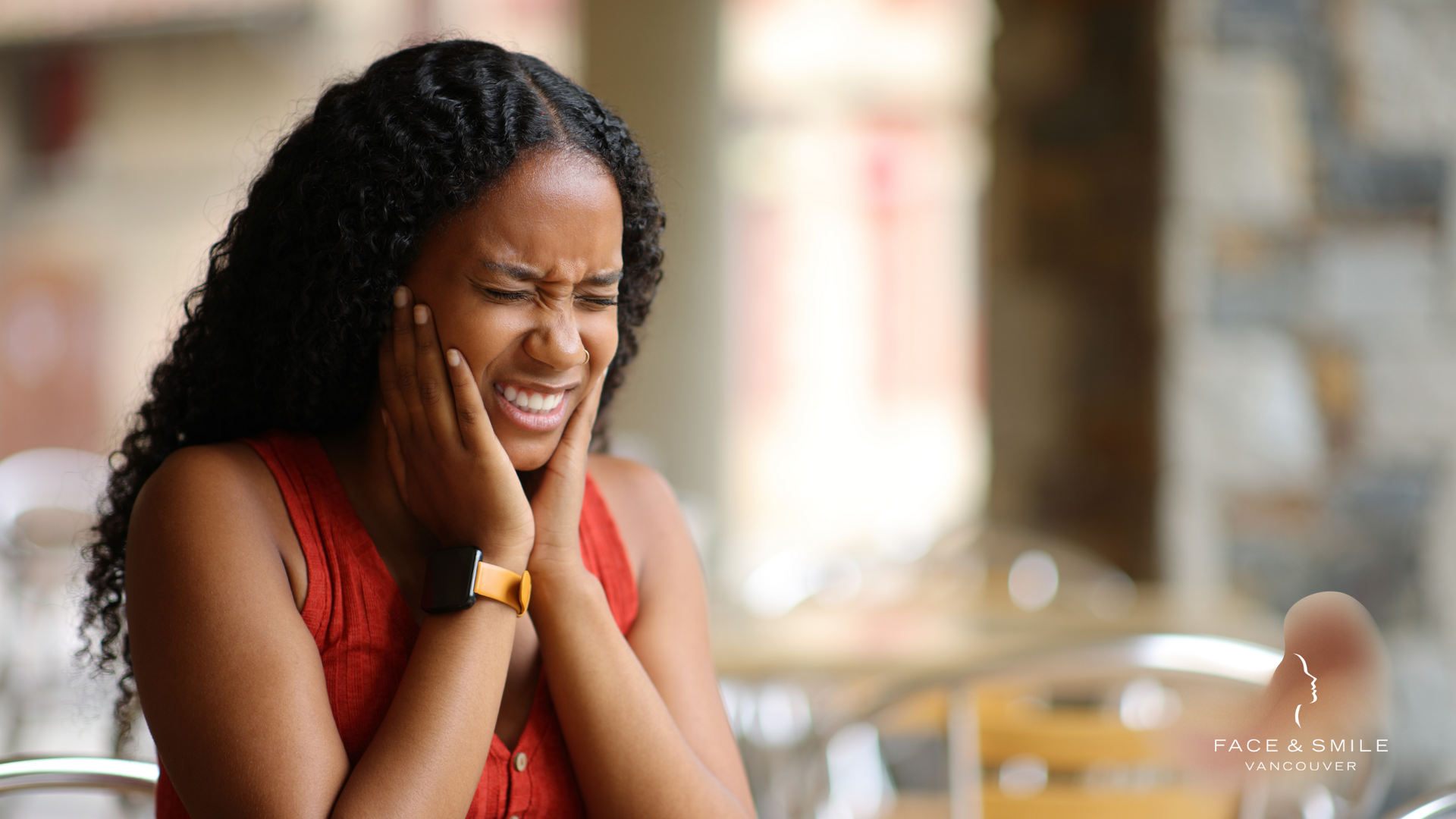 A woman is sitting at a table with her hands on her face.